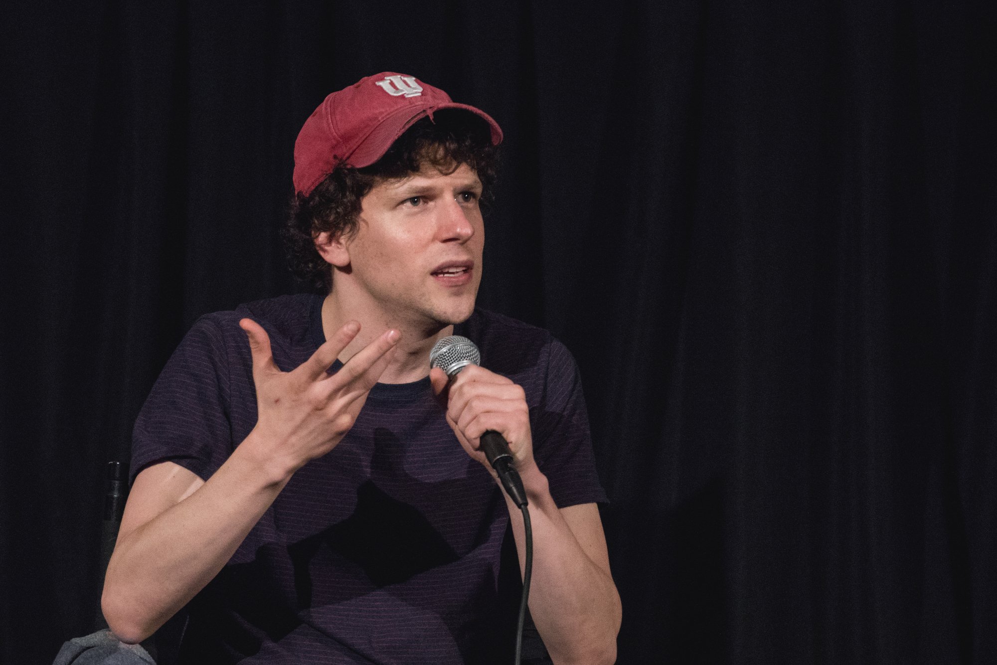 'When You Finish Saving the World' Jesse Eisenberg title holding a microphone and wearing a hat