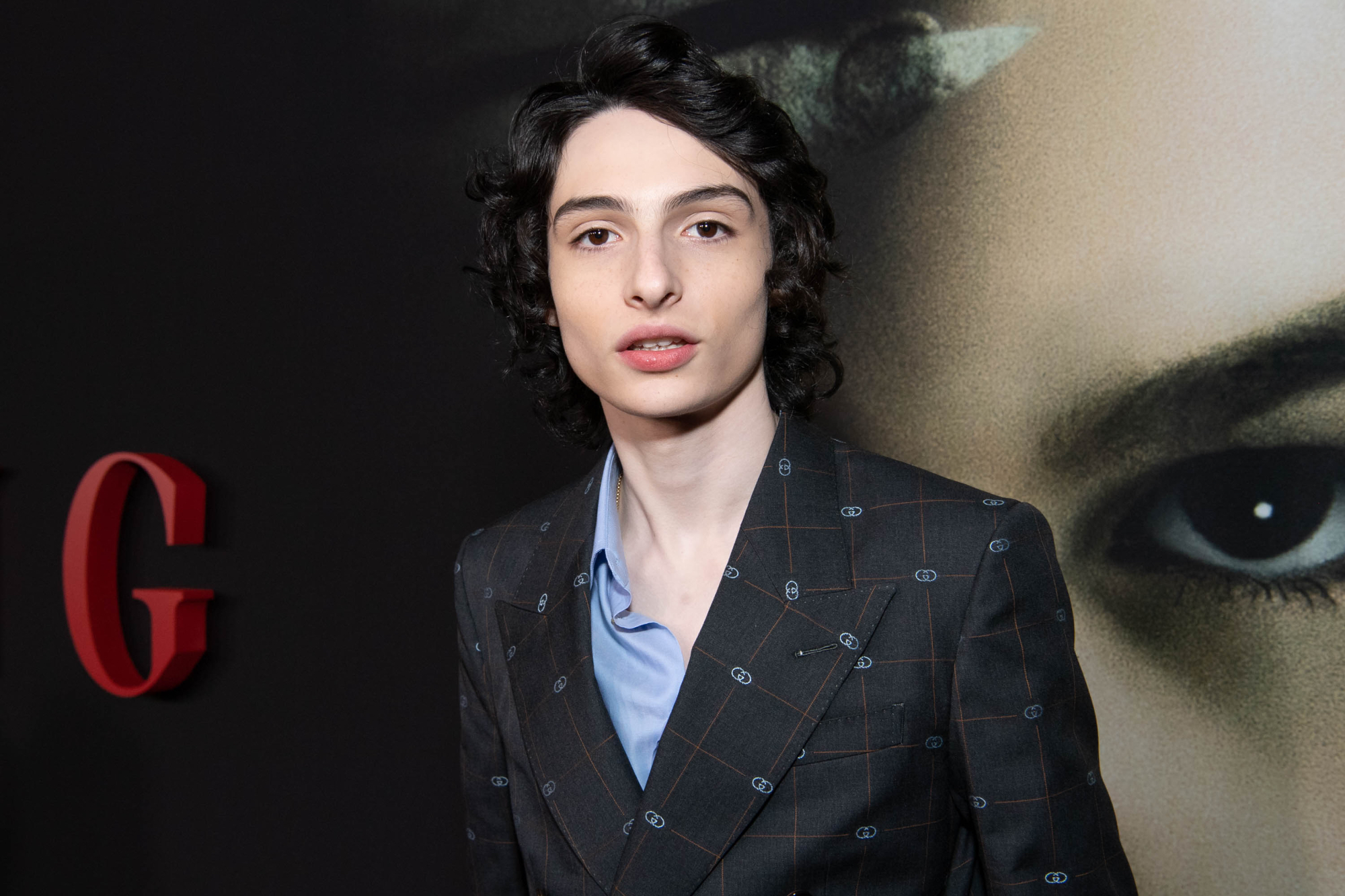 'When You Finish Saving the World' star Finn Wolfhard standing in front of 'The Turning' poster