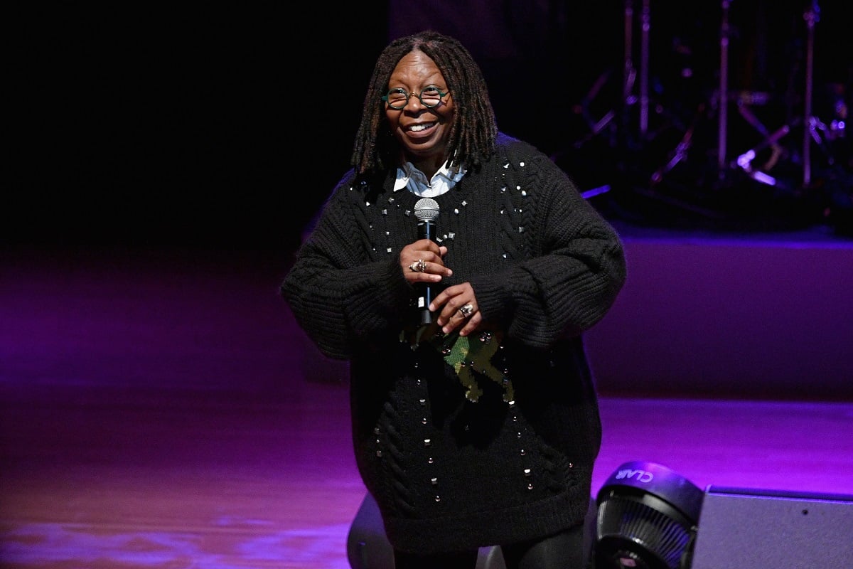 Whoopi Goldberg smiling while wearing a black sweater.