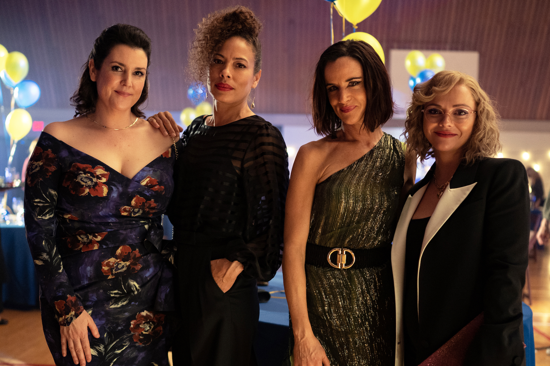 Melanie Lynskey as Shauna, Tawny Cypress as Taissa, Juliette Lewis as Natalie, and Christina Ricci as Misty from the 'Yellowjackets' cast standing side by side in formal clothing and smiling