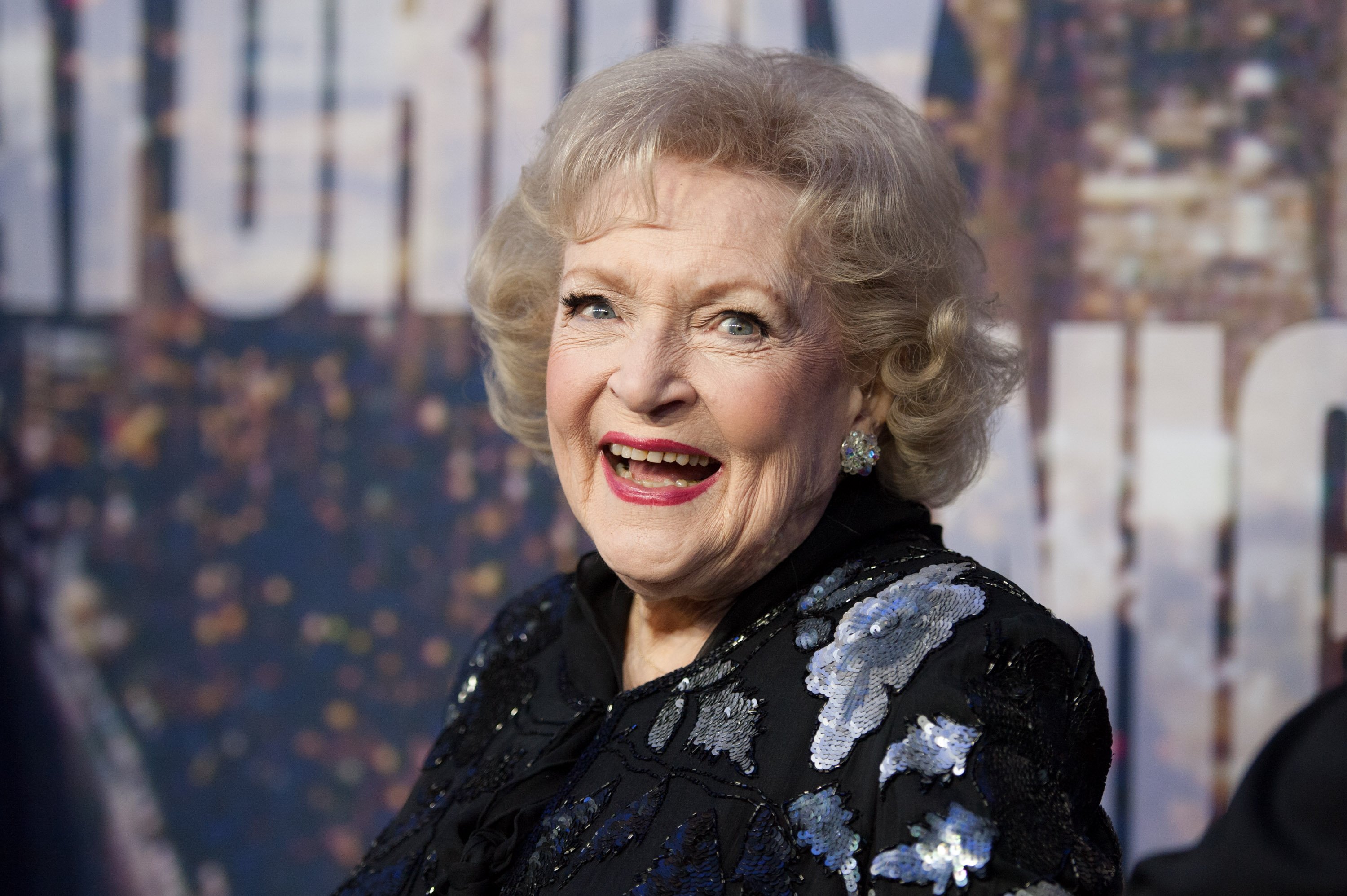 Betty White poses in a black outfit while smiling. 