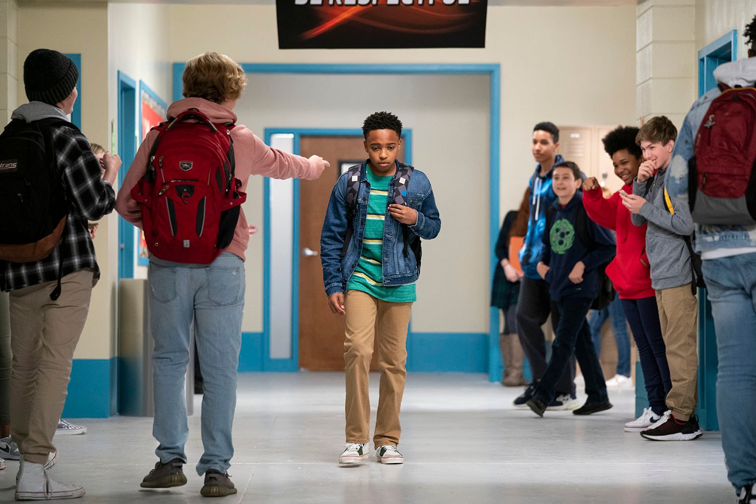 Dallas Dupree Young as Kenny, walking down a hallway just before Lia passes through in 'Cobra Kai' Season 4.