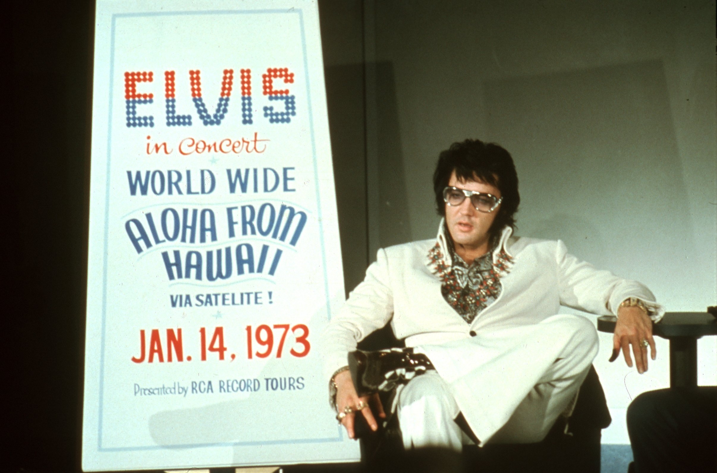 Elvis Presley in front of a poster