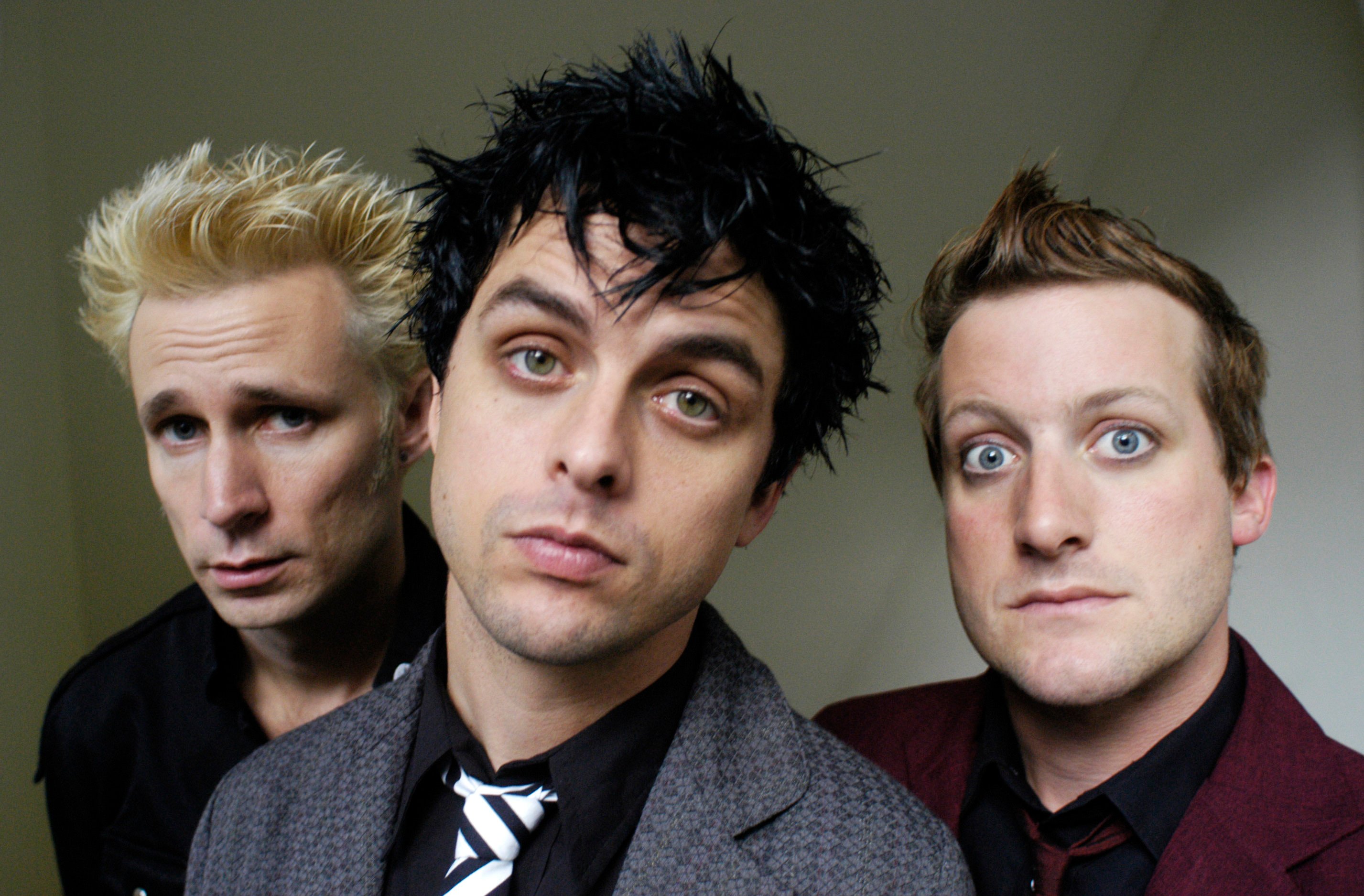 Green Day's Mike Dirnt, Billie Joe Armstrong, and Tré Cool with a grey background