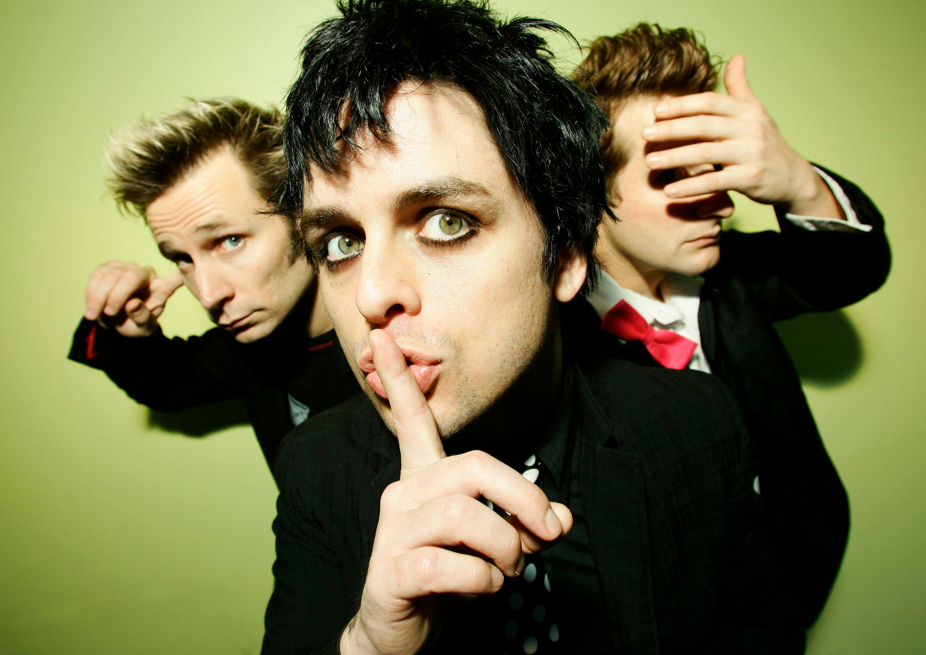 Green Day's Mike Dirnt, Billie Joe Armstrong, and Tré Cool with a green background