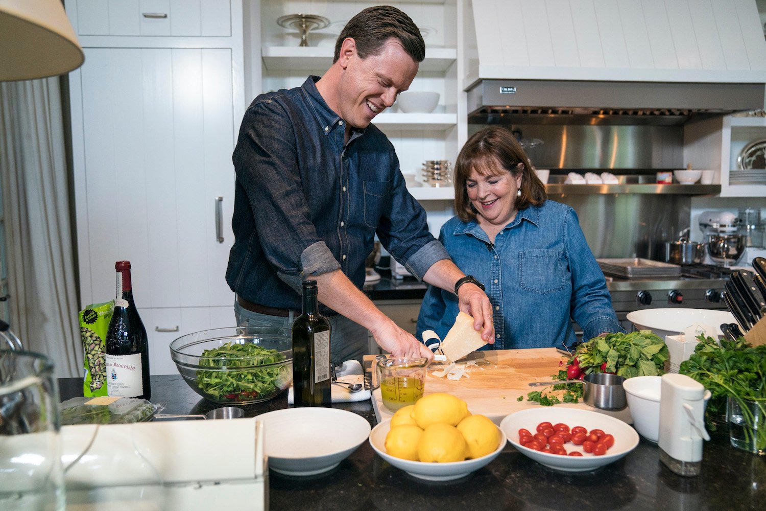 Ina Garten wears a denim blue shirt while she watches Willie Geist prepare food in her kitchen during an interview for Sunday Today.