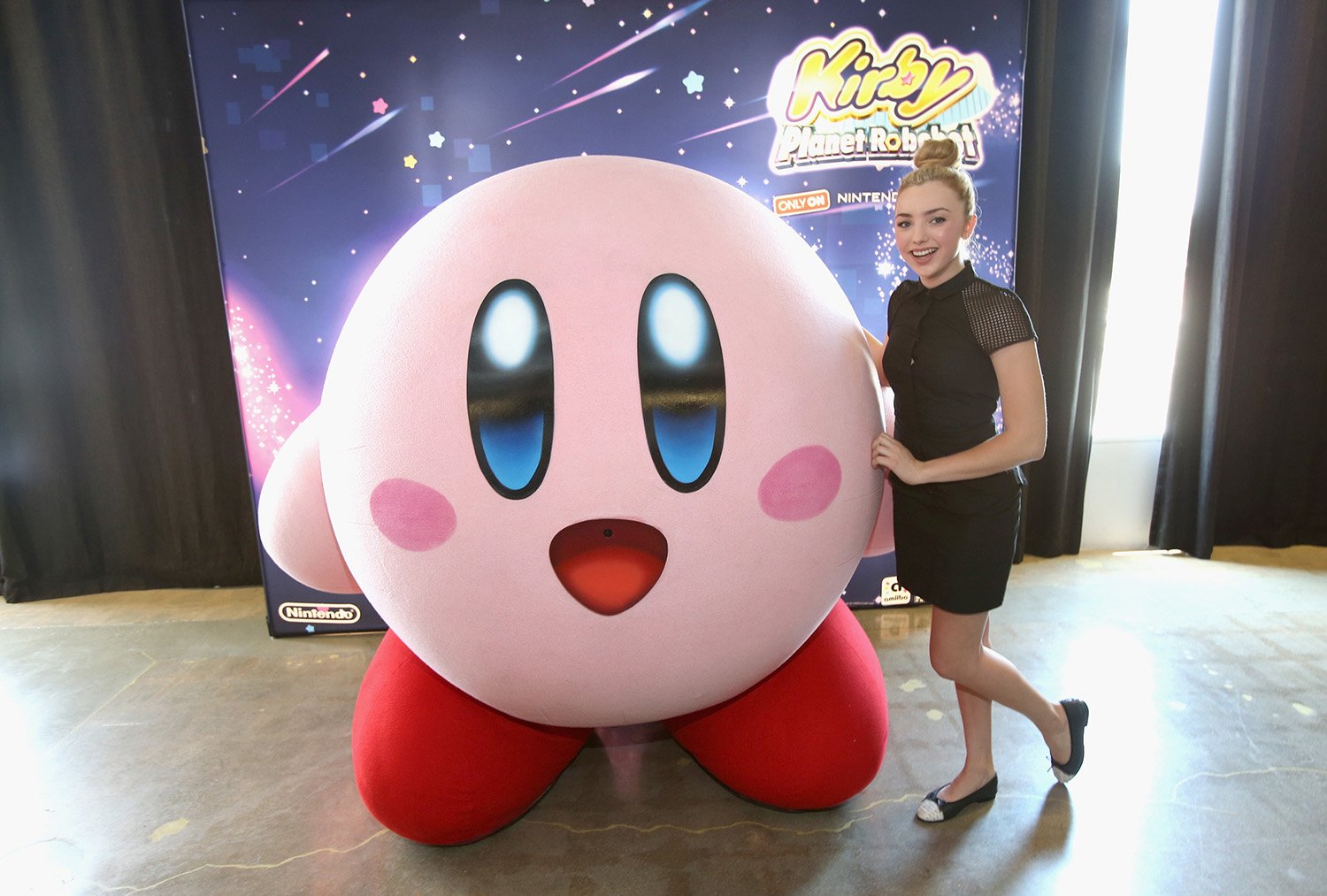 Actor Peyton List stands beside a Kirby statue at the Kirby: Planet Robobot games launch event