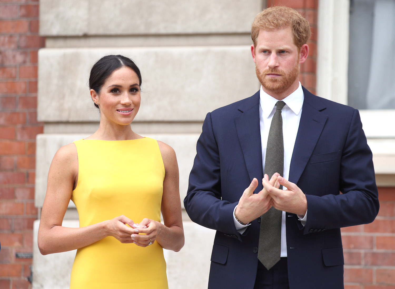 Meghan Markle and Prince Harry wearing a yellow dress and suit, respectively, during the Your Commonwealth Youth Challenge reception in 2018