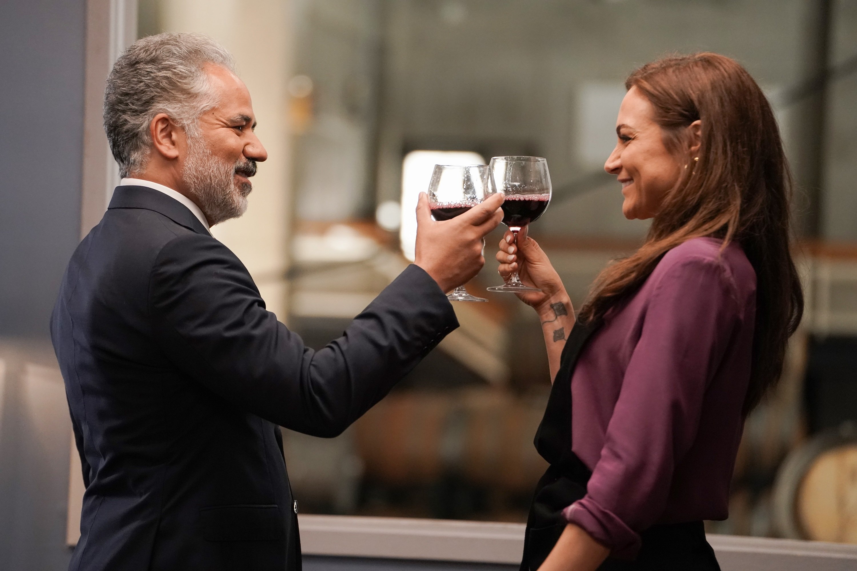 'Promised Land' cast members John Ortiz and Christina Ochoa as Joe and Veronica Sandoval smile at each other while holding up glasses of wine.