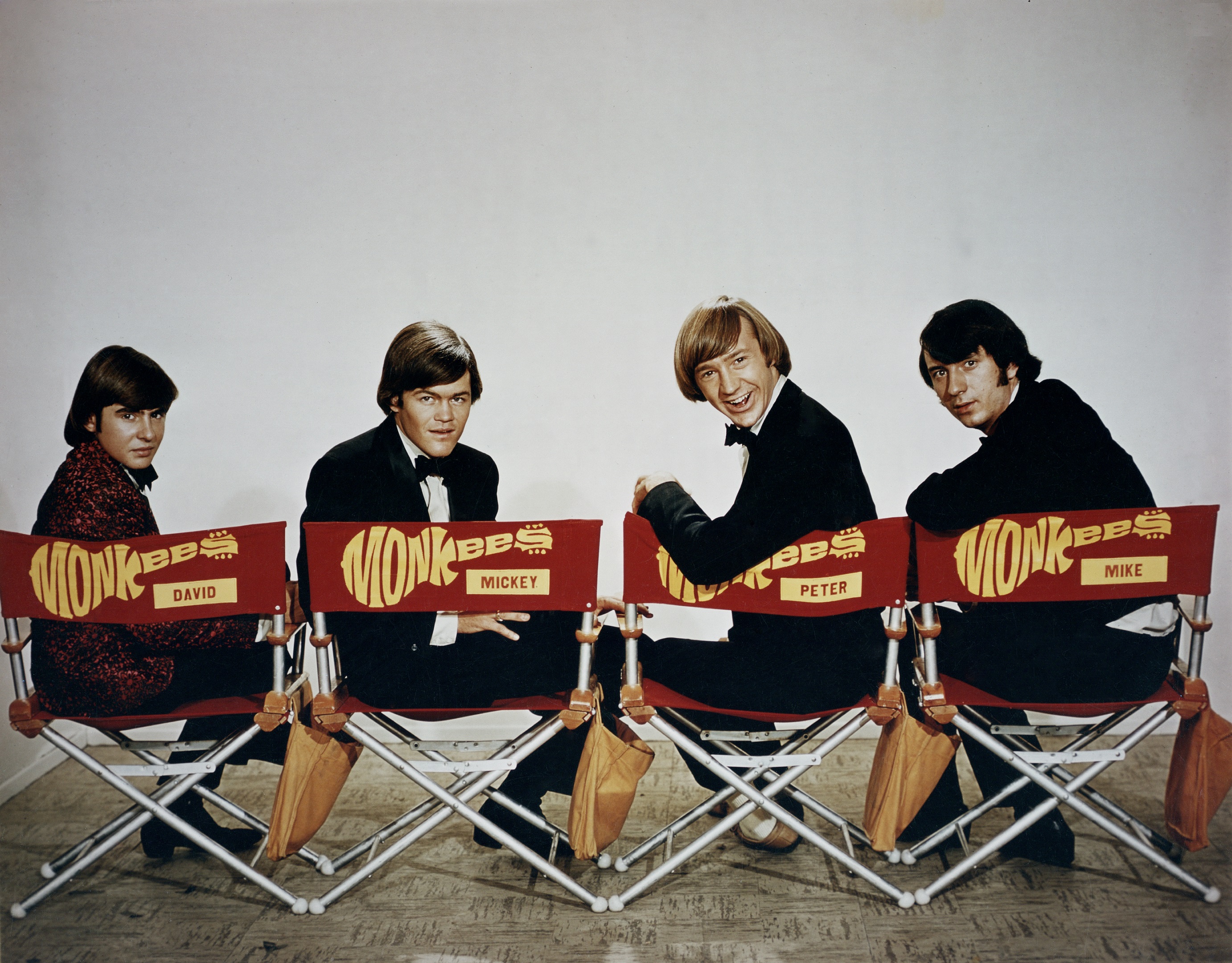 The Monkees' Davy Jones, Micky Dolenz, Peter Tork, and Mike Nesmith sitting in chairs