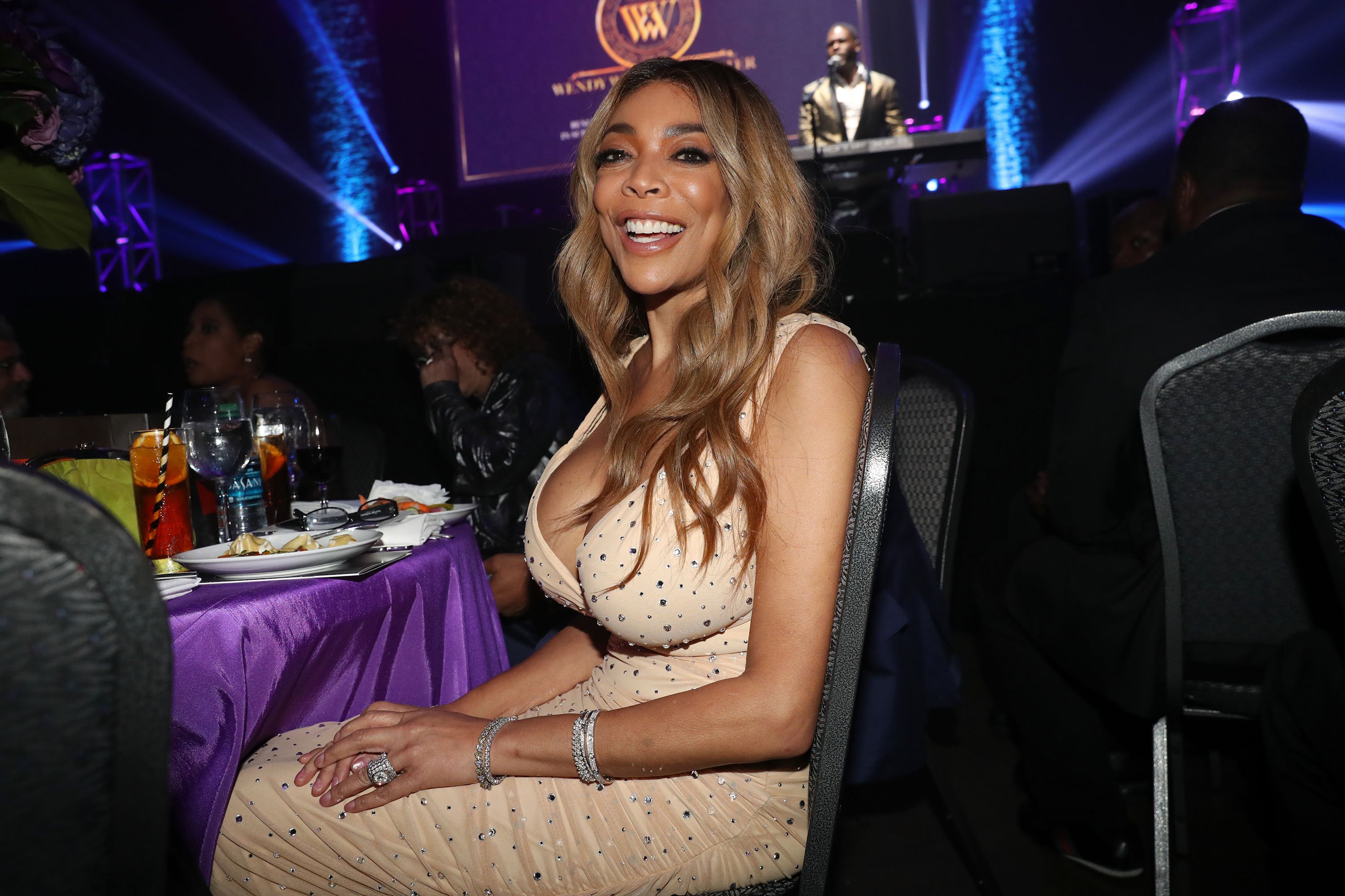 Wendy Williams smiling as she sits in a chair