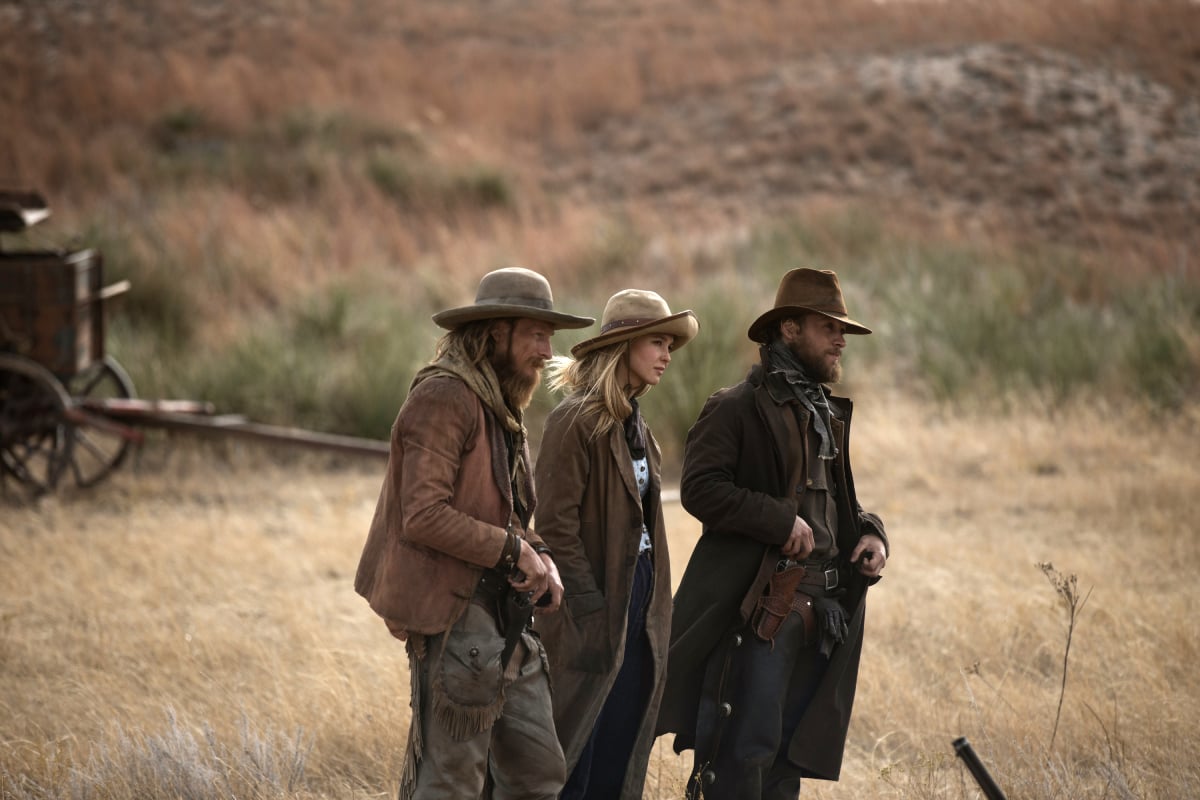 James Landry Hebert as Wade, Isabel May as Elsa, and Noah Le Gros as Colton. The trio stand next to each other in the brown grass.