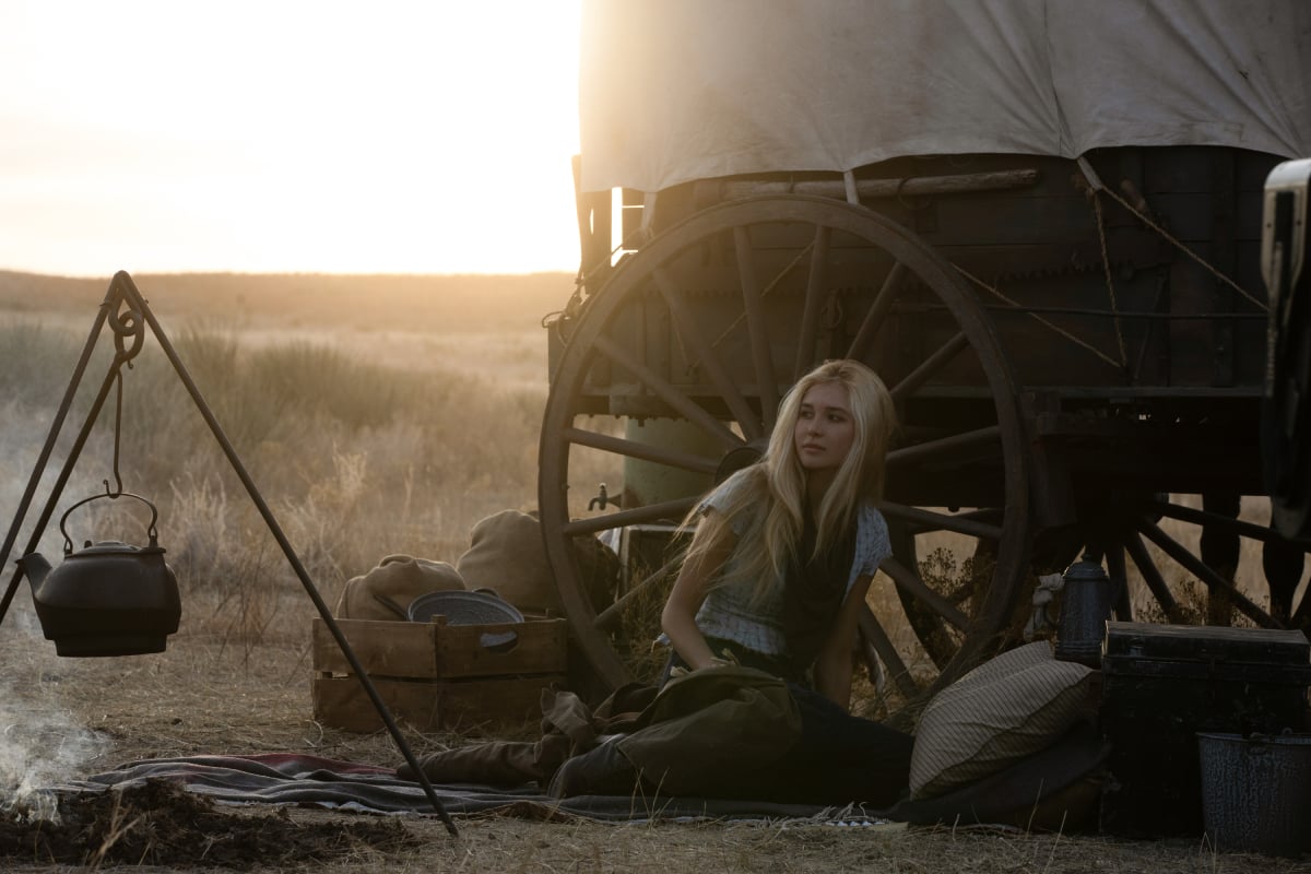 1883 Isabel May as Elsa Dutton sitting down by their covered wagon in the Yellowstone prequel