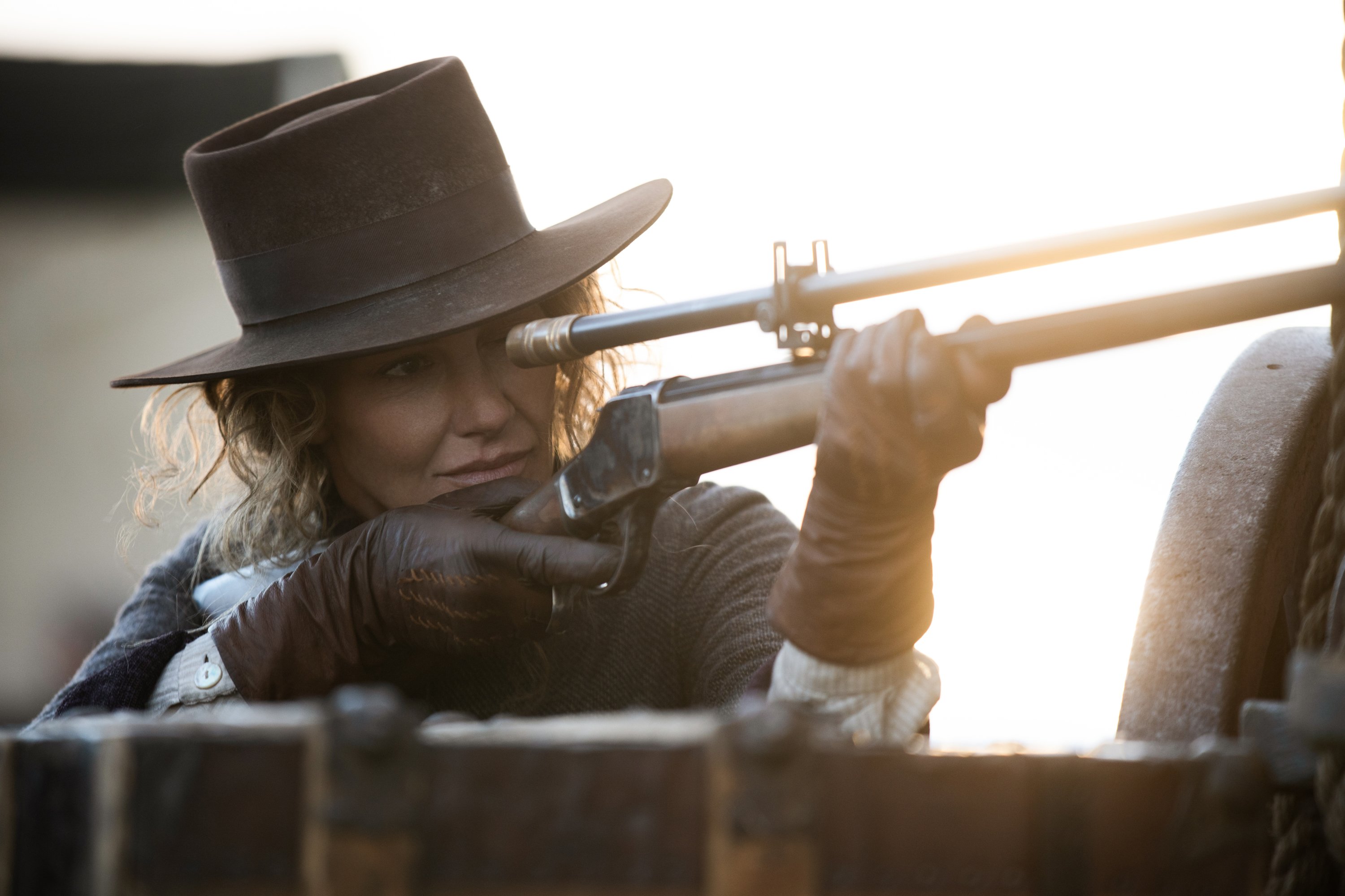 Faith Hill as Margaret in 1883 Episode 9. Margaret wears a hat and aims a rifle.