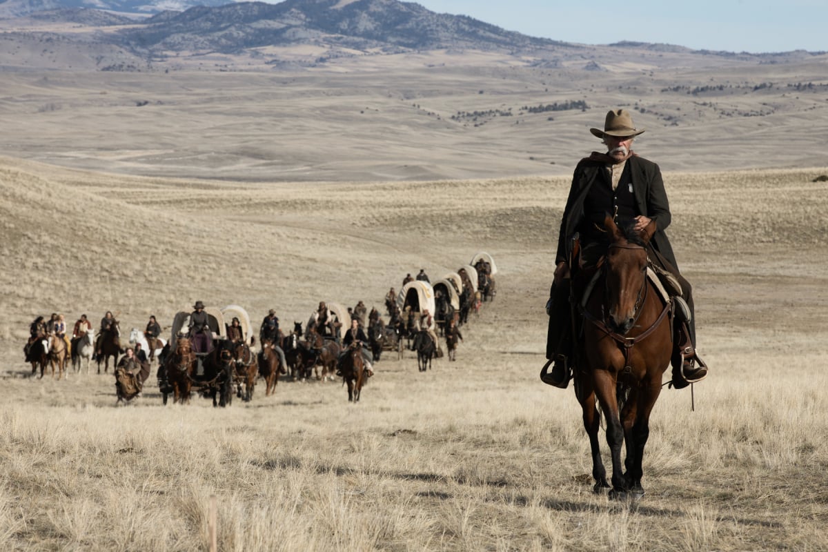 Sam Elliott as Shea of the Paramount+ original series 1883. Shea rides his horse in front of the wagon train.