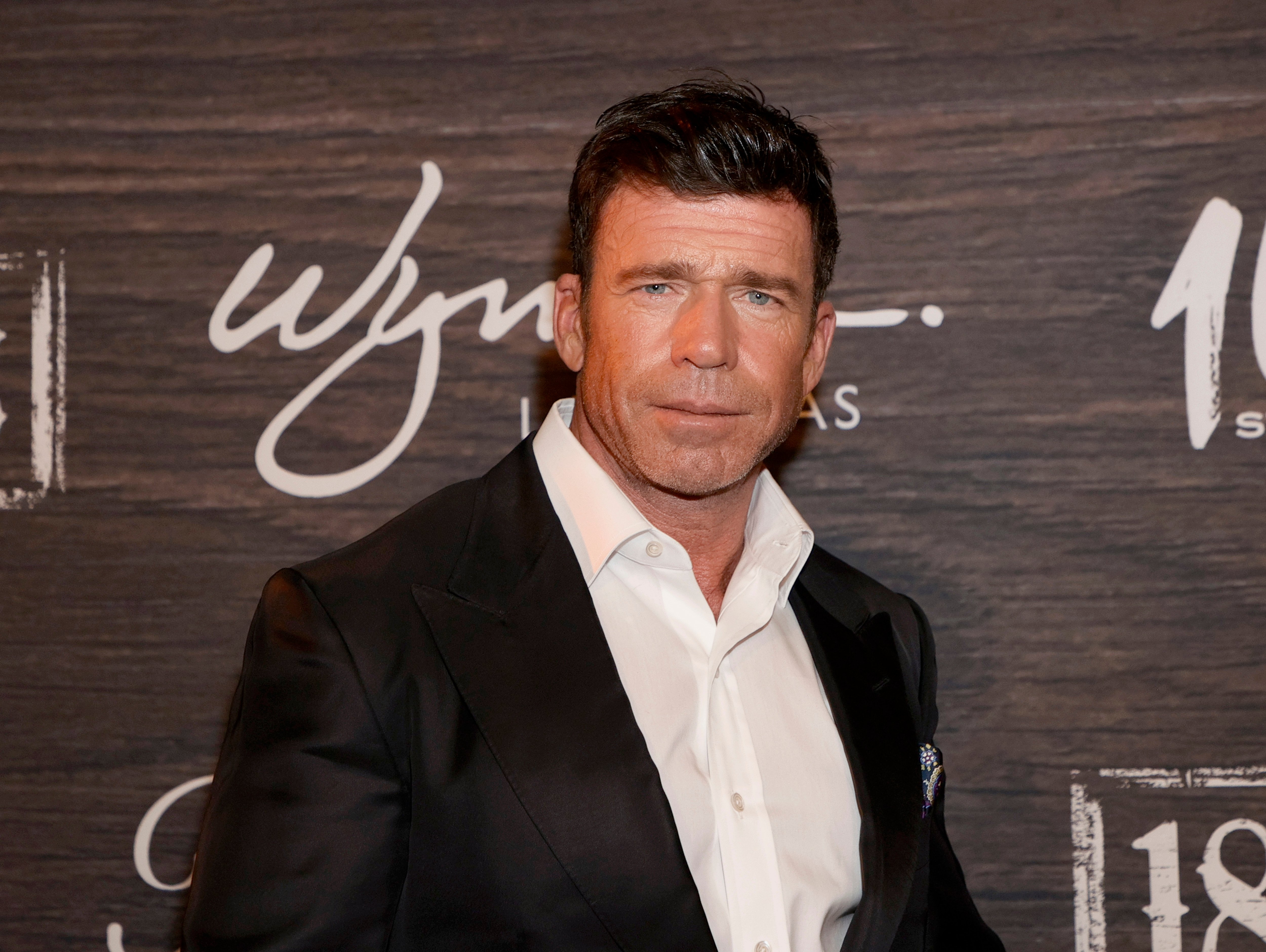 Taylor Sheridan attends the world premiere of '1883' at Encore Beach Club at Wynn Las Vegas on December 11, 2021 in Las Vegas, Nevada. Sheridan wears a white collared shirt and black suit jacket.
