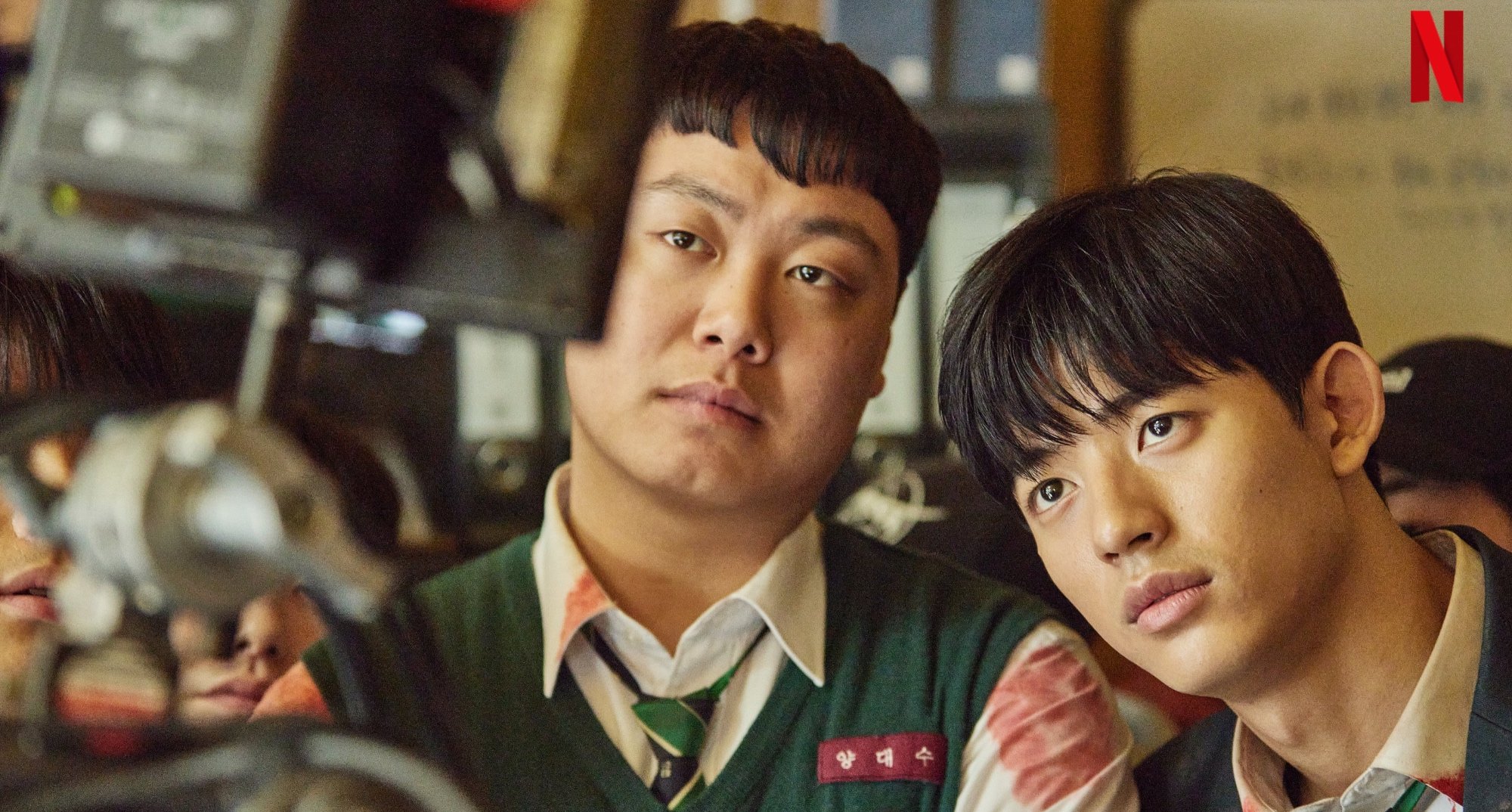 Actors Im Jae-hyuk and Park Solomon in 'All of Us Are Dead' looking at camera monitor.