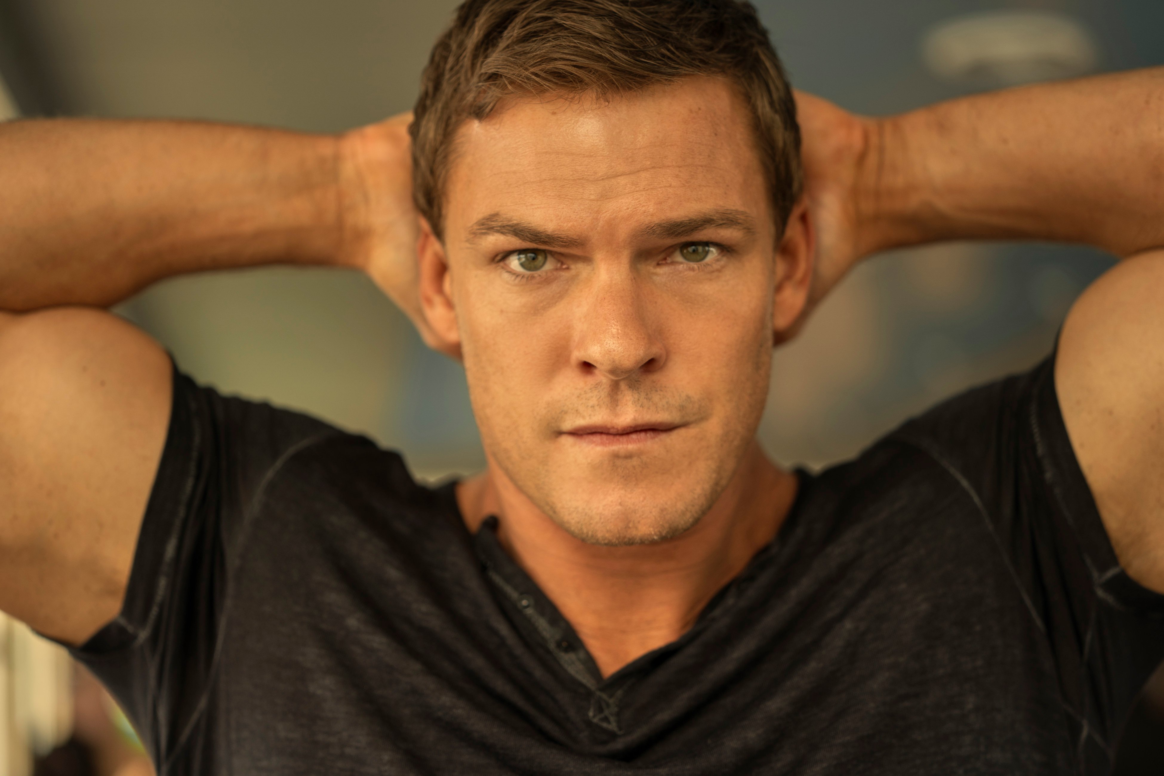 Alan Ritchson as Jack Reacher, with his hands behind his head
