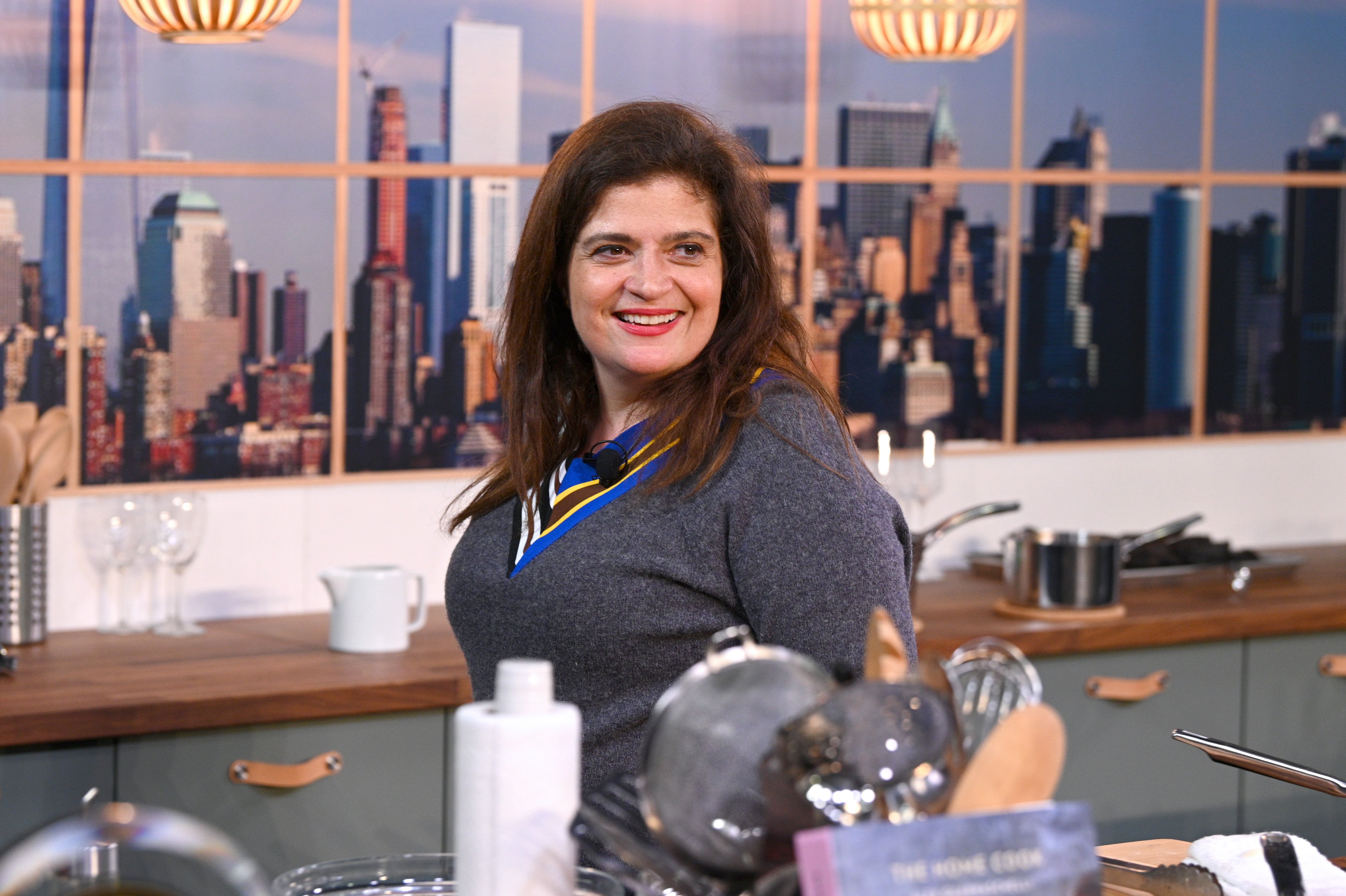 Food Network chef Alex Guarnaschelli wears a blue sweater as she prepares a dish.
