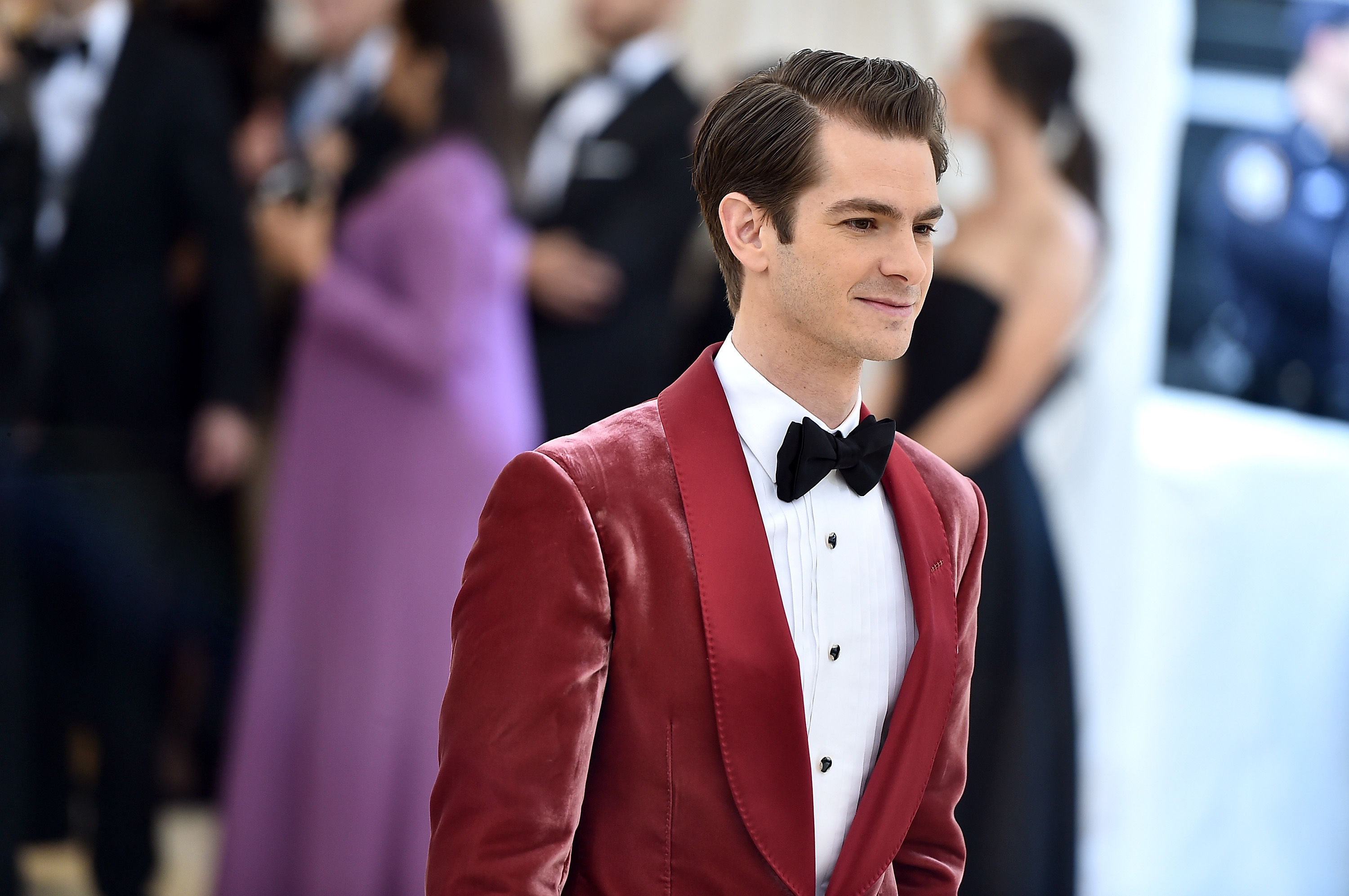 Andrew Garfield, who stars alongside Tobey Maguire in 'Spider-Man: No Way Home,' wears a red suit jacket over a white button-up shirt and black bow tie.