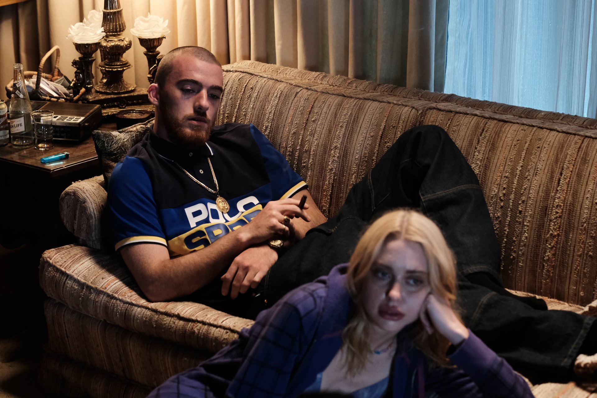 Angus Cloud as Fez and Chloe Cherry as Faye lying on and in front of a couch in 'Euphoria' Season 2 