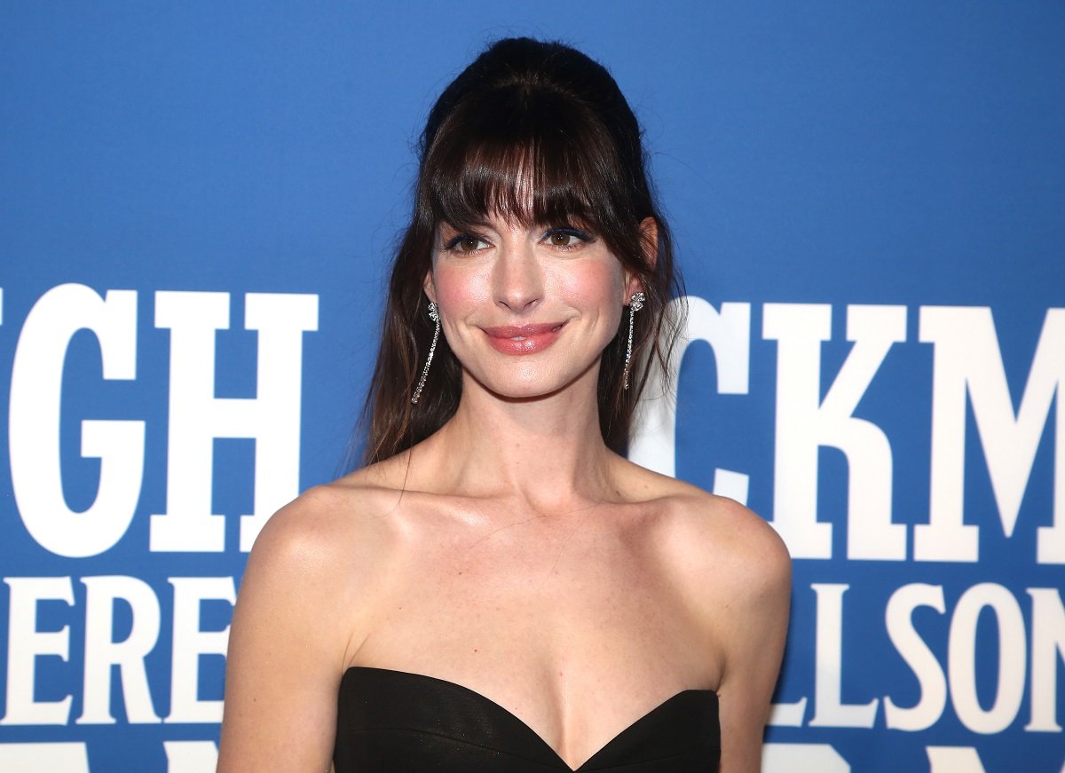 Anne Hathaway smiling while wearing a black dress.