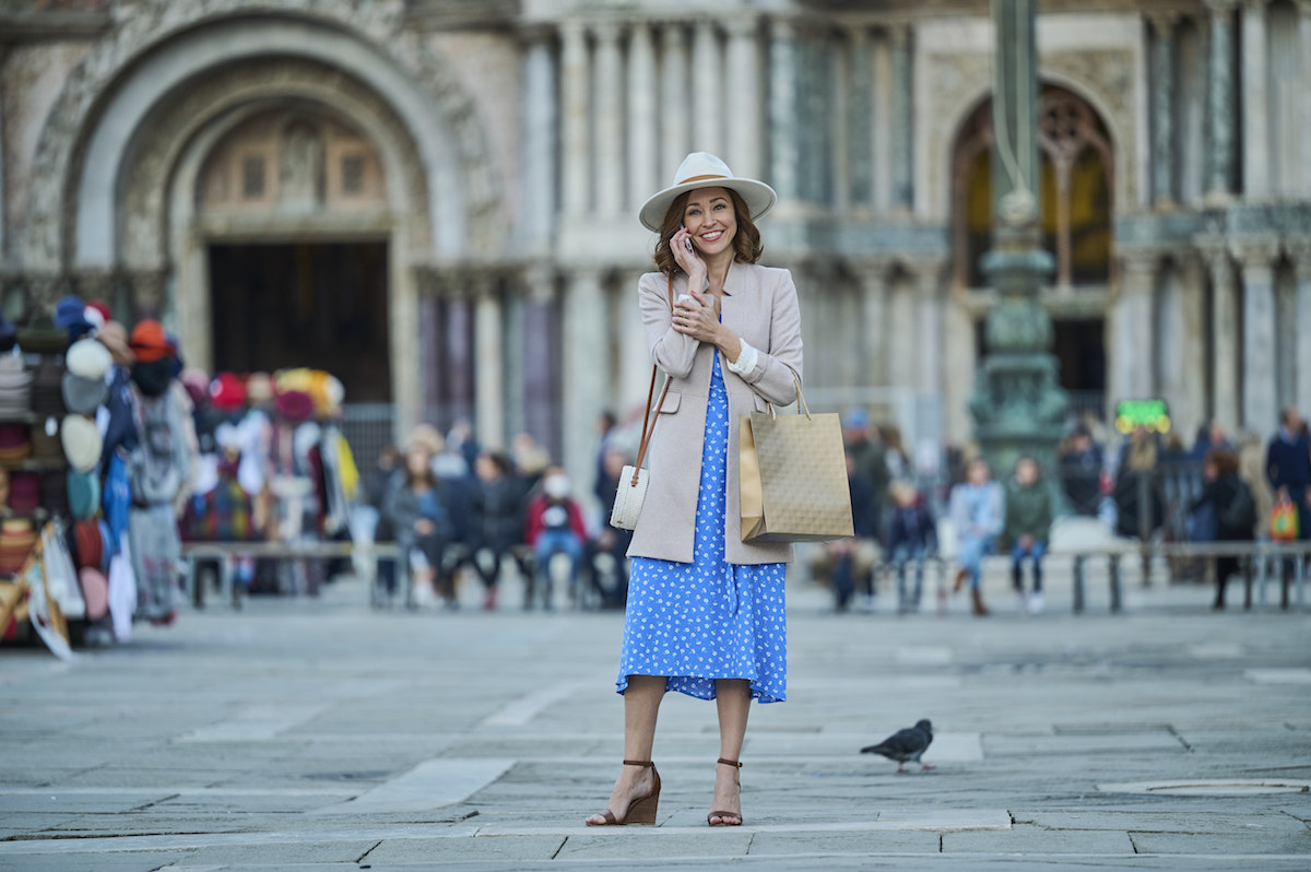 Autumn Reeser, wearing a hat and talking on the phone, in St Mark's Square in 'The Wedding Veil Unveiled' 
