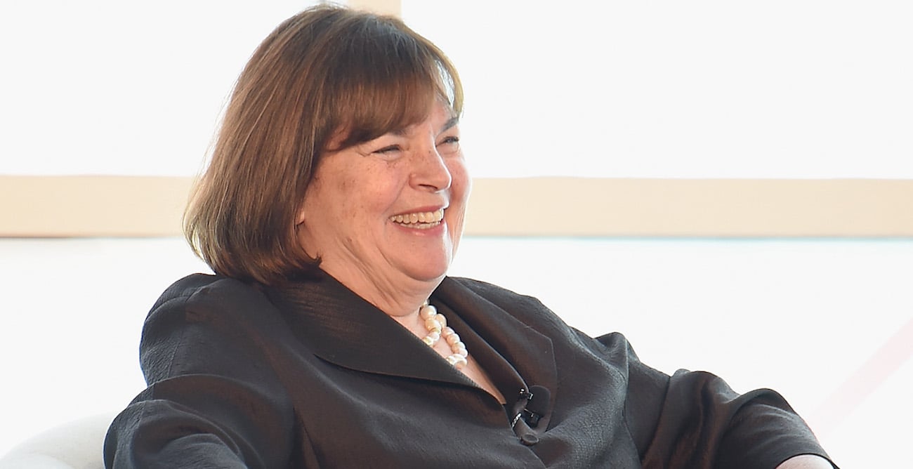 Ina Garten smiles and looks on wearing a black shirt