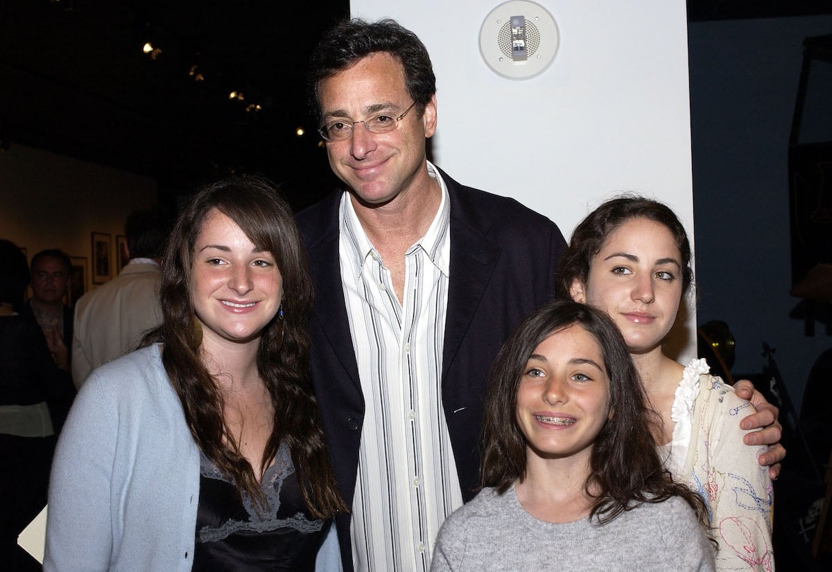 Bob Saget and his three daughters pose together at an event.