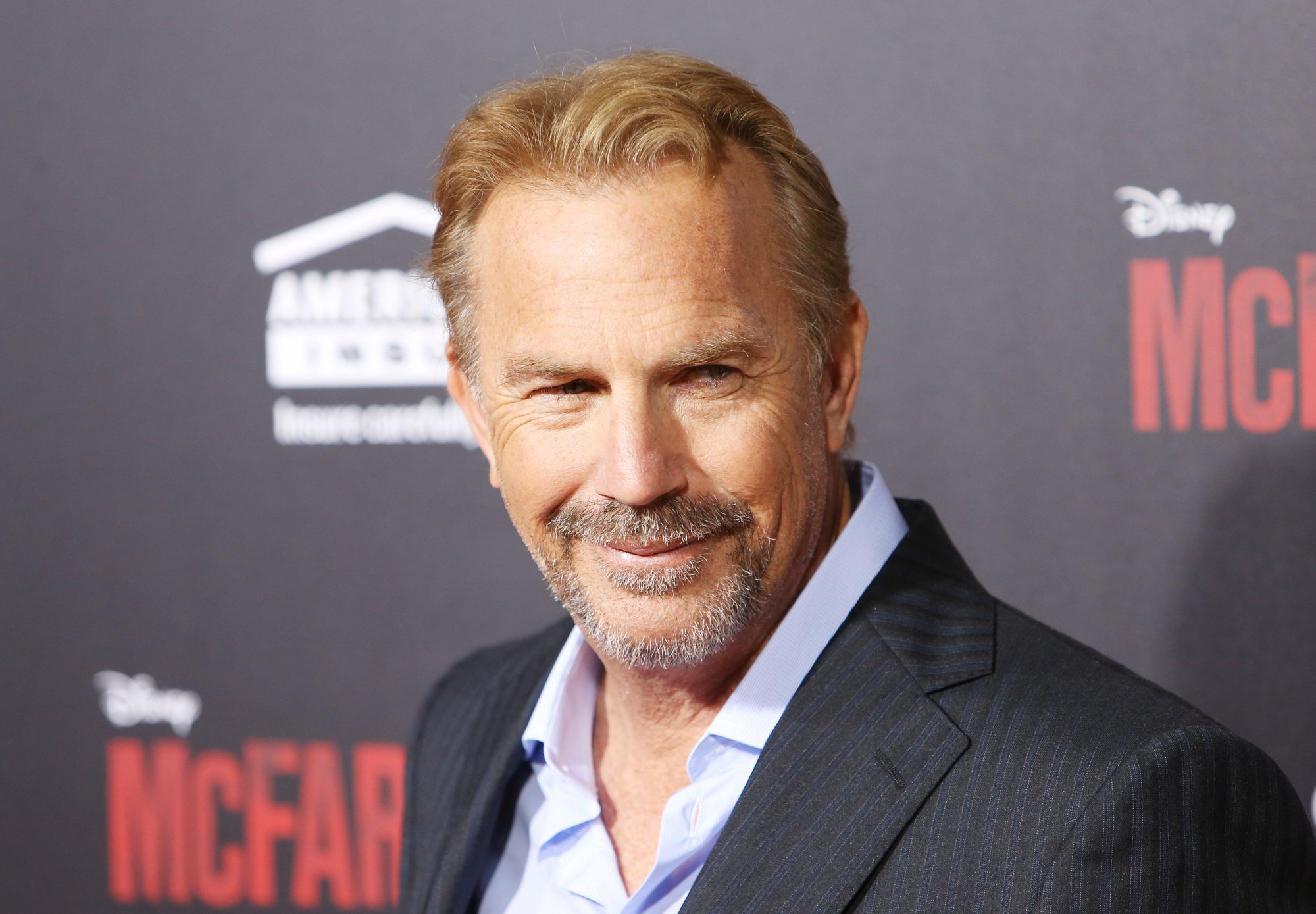 'Bull Durham' actor Kevin Costner standing in front of black step and repeat