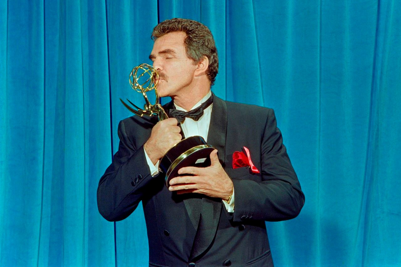 Burt Reynolds, in a tuxedo, kisses his Emmy statuette for his role in "Evening Shade"