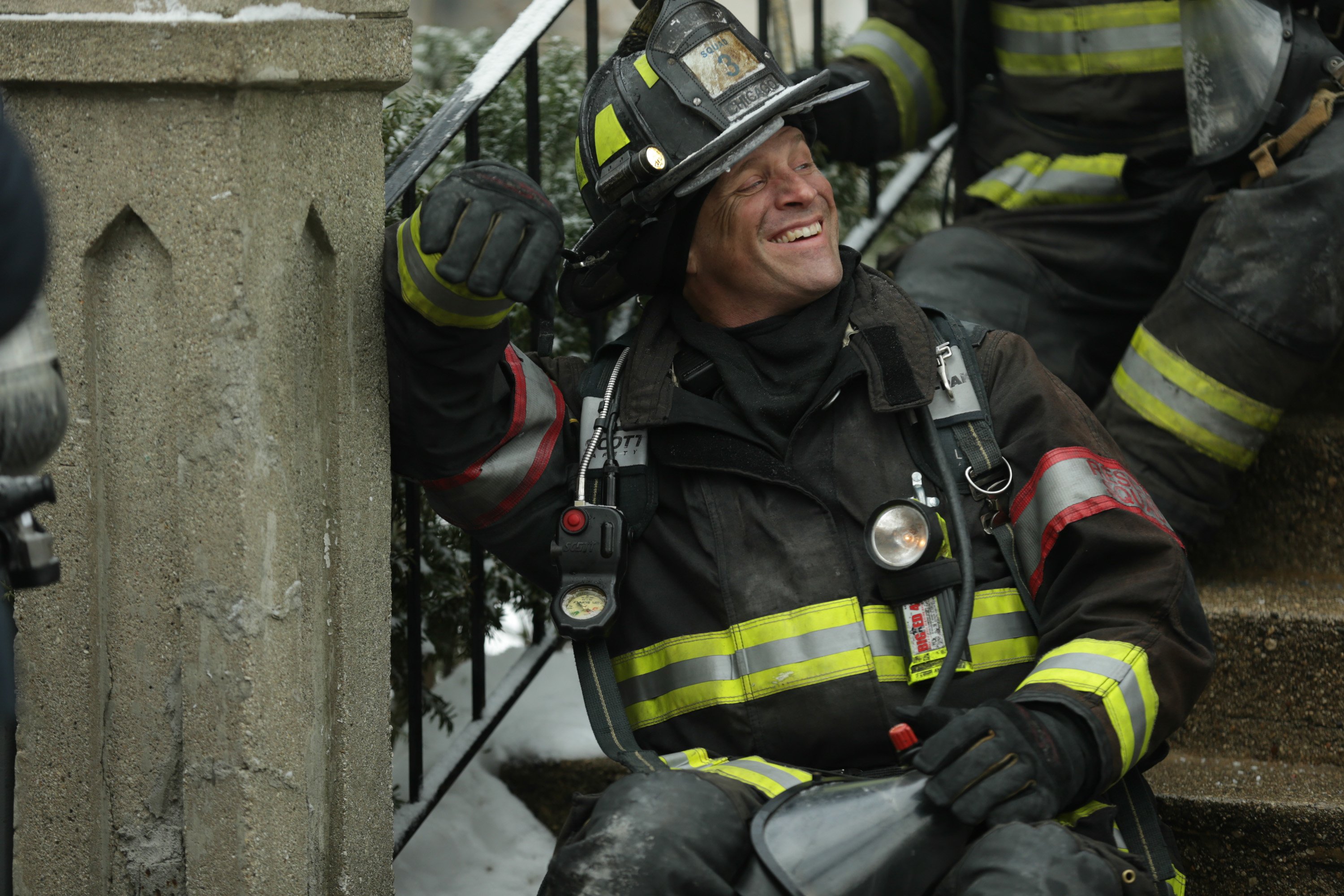 Capp sits on the stairs in his fireman gear smiling. Randy Flagler reveals Capp's secret talent in Chicago Fire Season 10 Episode 12.