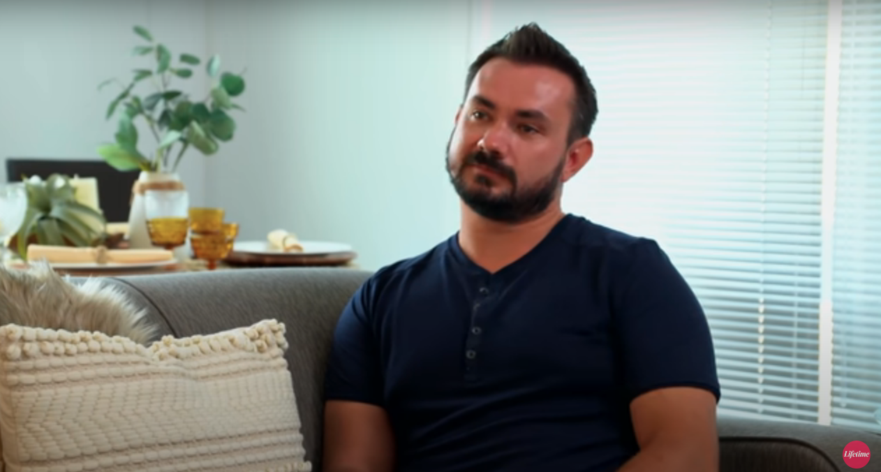 Chris, wearing a T-shirt and sitting on a couch in 'Married at First Sight'
