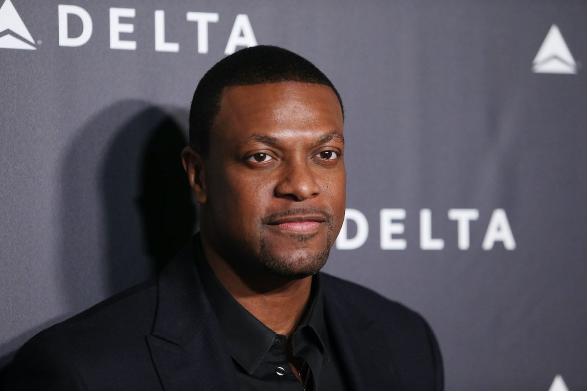 Chris Tucker wears black and poses on the red carpet