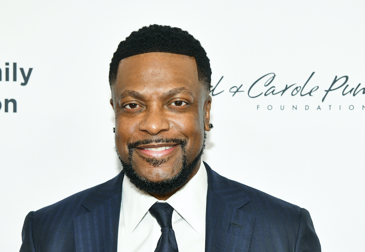 Chris Tucker wears a suit and smiles on the red carpet