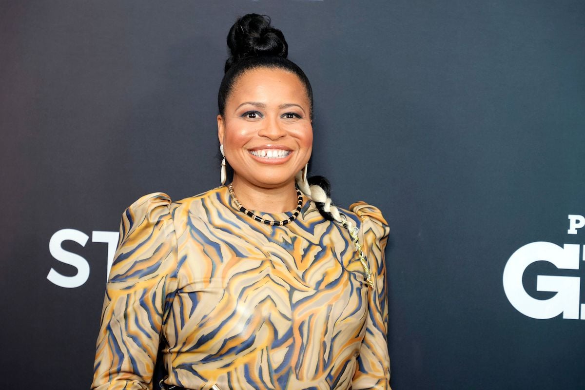 Courtney A. Kemp attends the "Power Book II: Ghost" Season 2 Premiere wearing a gold dress and a top knot