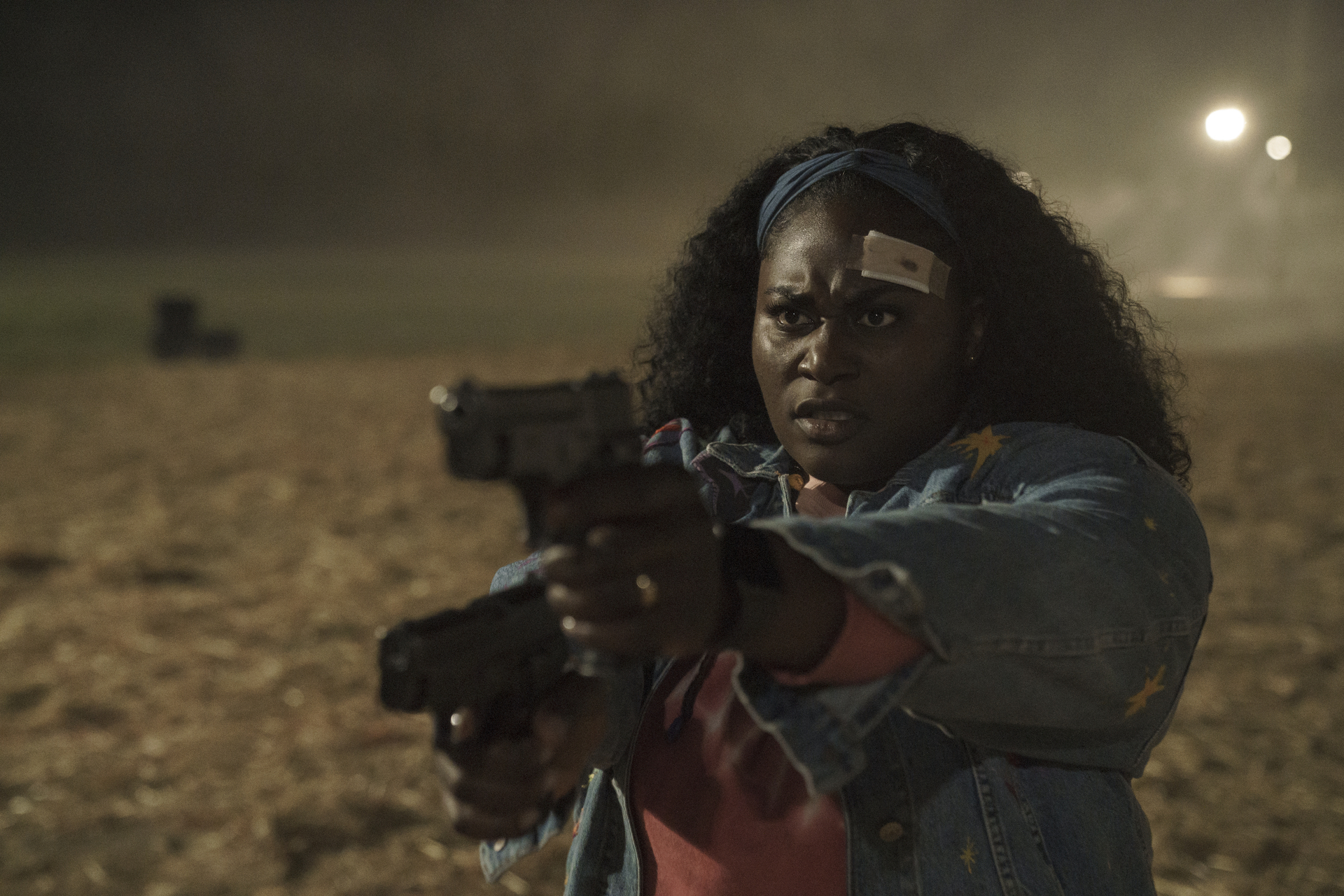 Danielle Brooks as Leota Adebayo in DC's 'Peacemaker' Episode 8. Her head has a bandage on it and she's holding a gun.