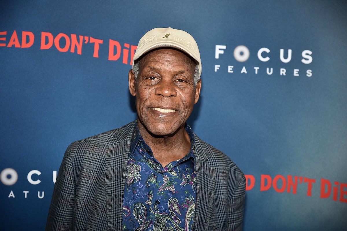 Danny Glover smiles in front of artwork for ‘The Dead Don’t Die’
