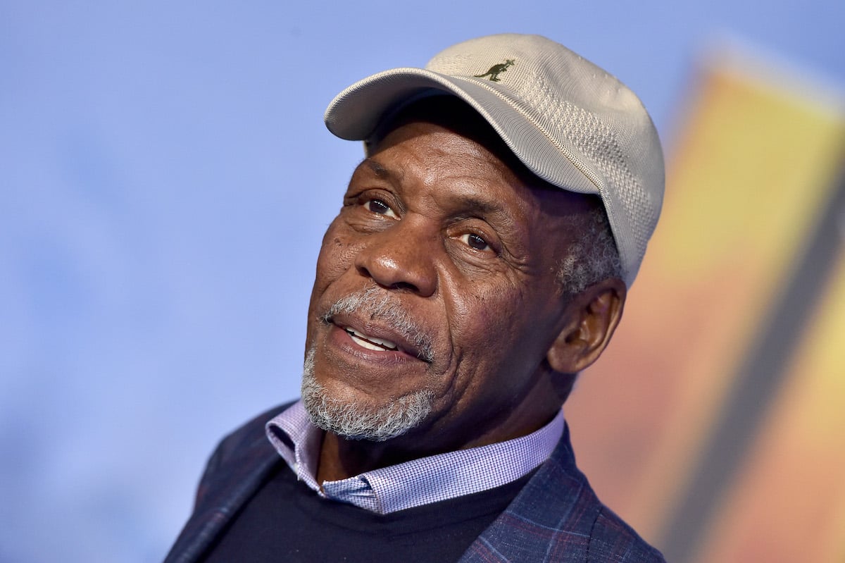 Danny Glover wears a cap and poses on the red carpet