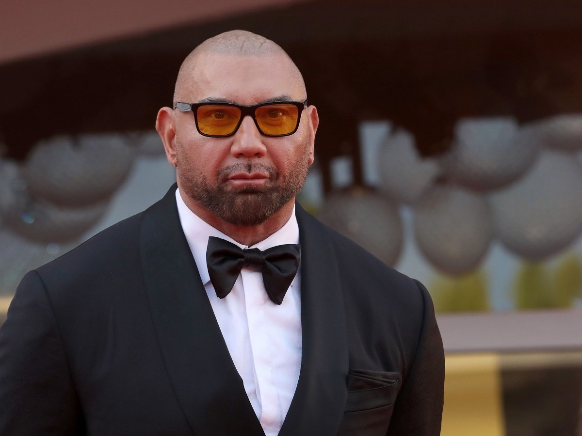 Dave Bautista posing in a suit while wearing sunglasses.