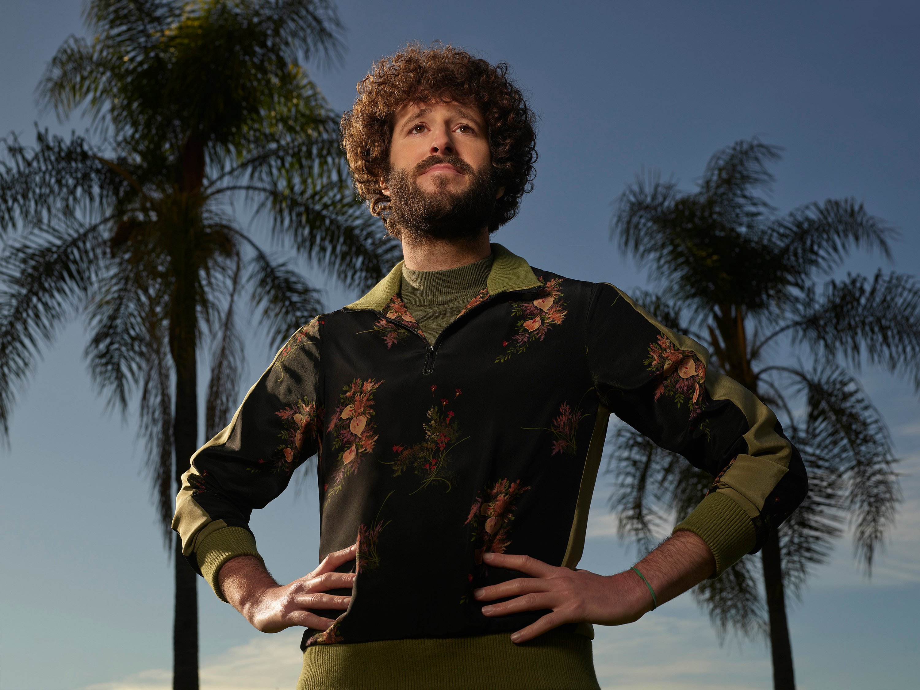 Dave 'Lil Dicky' Burd posing with his hands on his hips in front of palm trees for the FX series 'Dave'