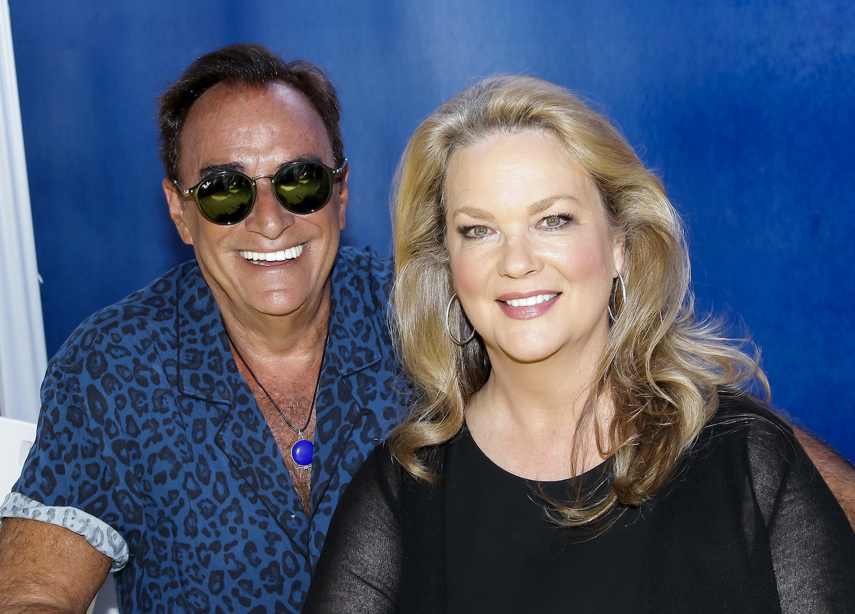 'Days of Our Lives' cast members Thaao Penghlis and Leann Hunley smiling in front of a blue backdrop