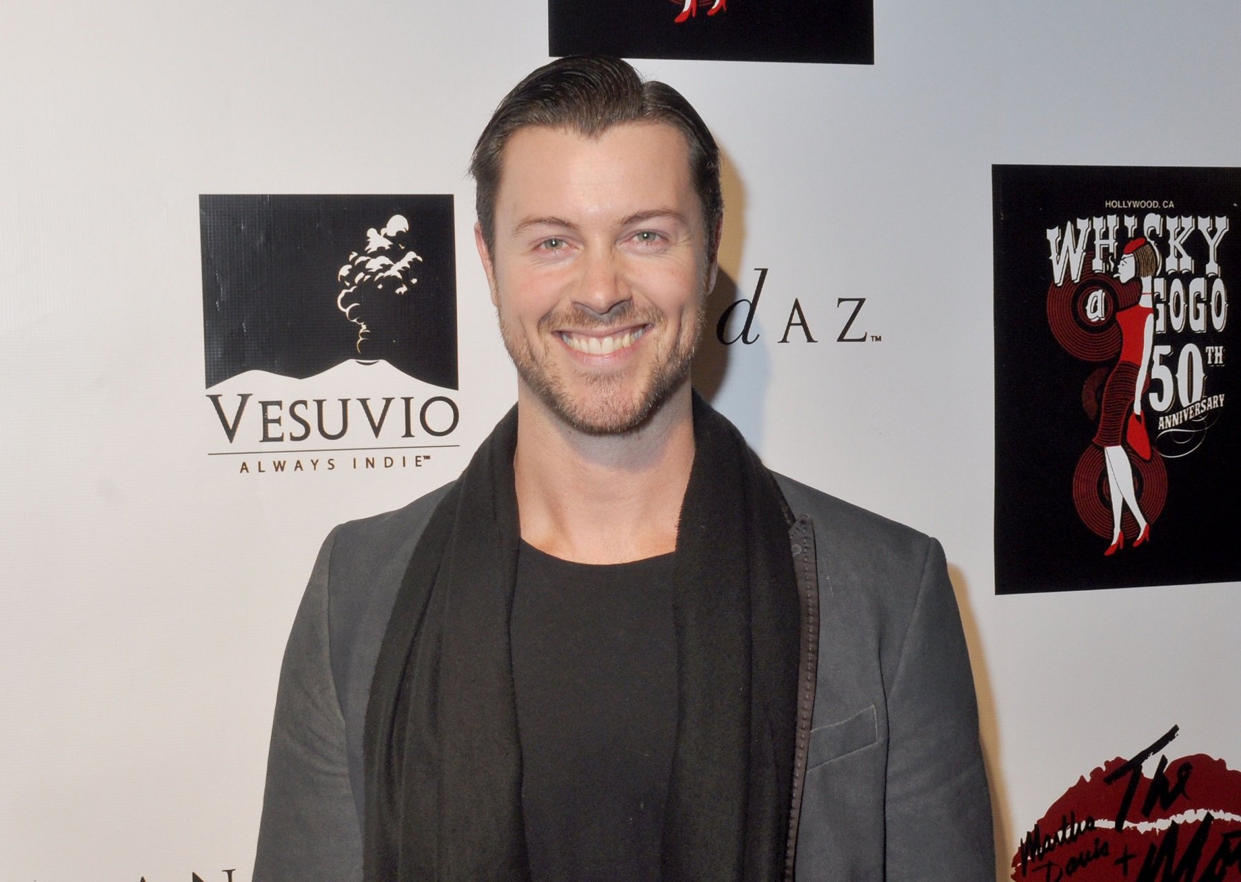 Days of Our Lives star Dan Feuerriegel, pictured here in a black shirt with a grey jacket and a black scarf