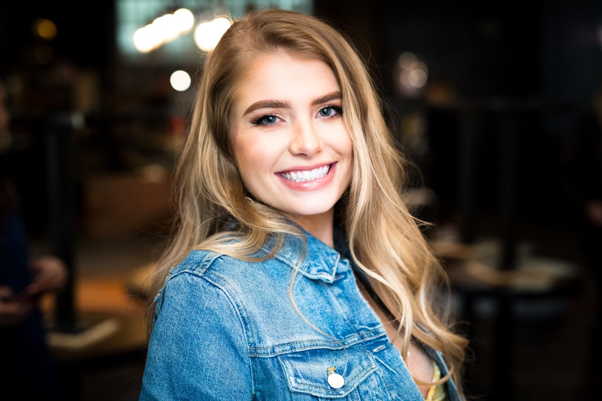 Demi Burnett smiles for the camera in a denim jacket.