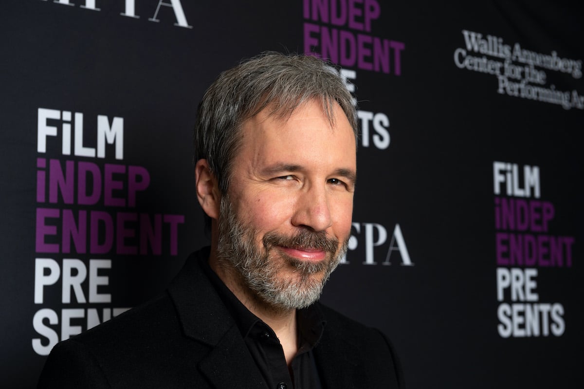 Denis Villeneuve wears a dark suit and smiles on the red carpet