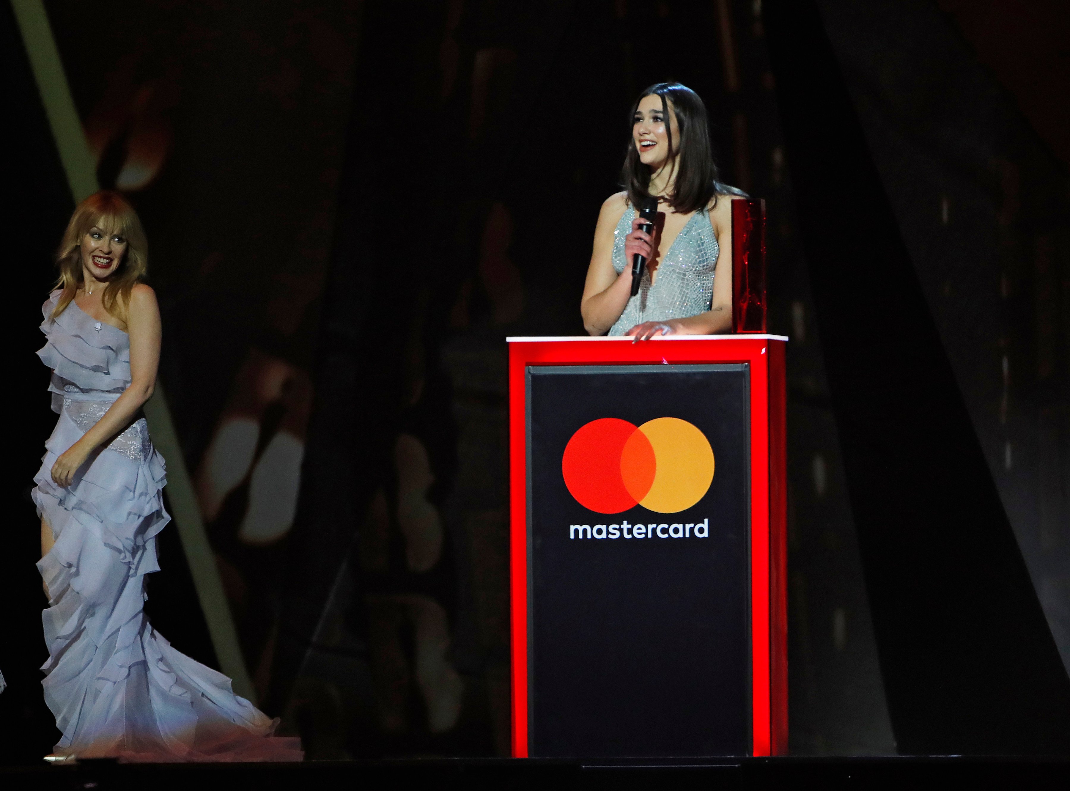 Dua Lipa, winner of the British Female Solo Artist award, speaks as Kylie Minogue (L) looks on at The BRIT Awards 2018