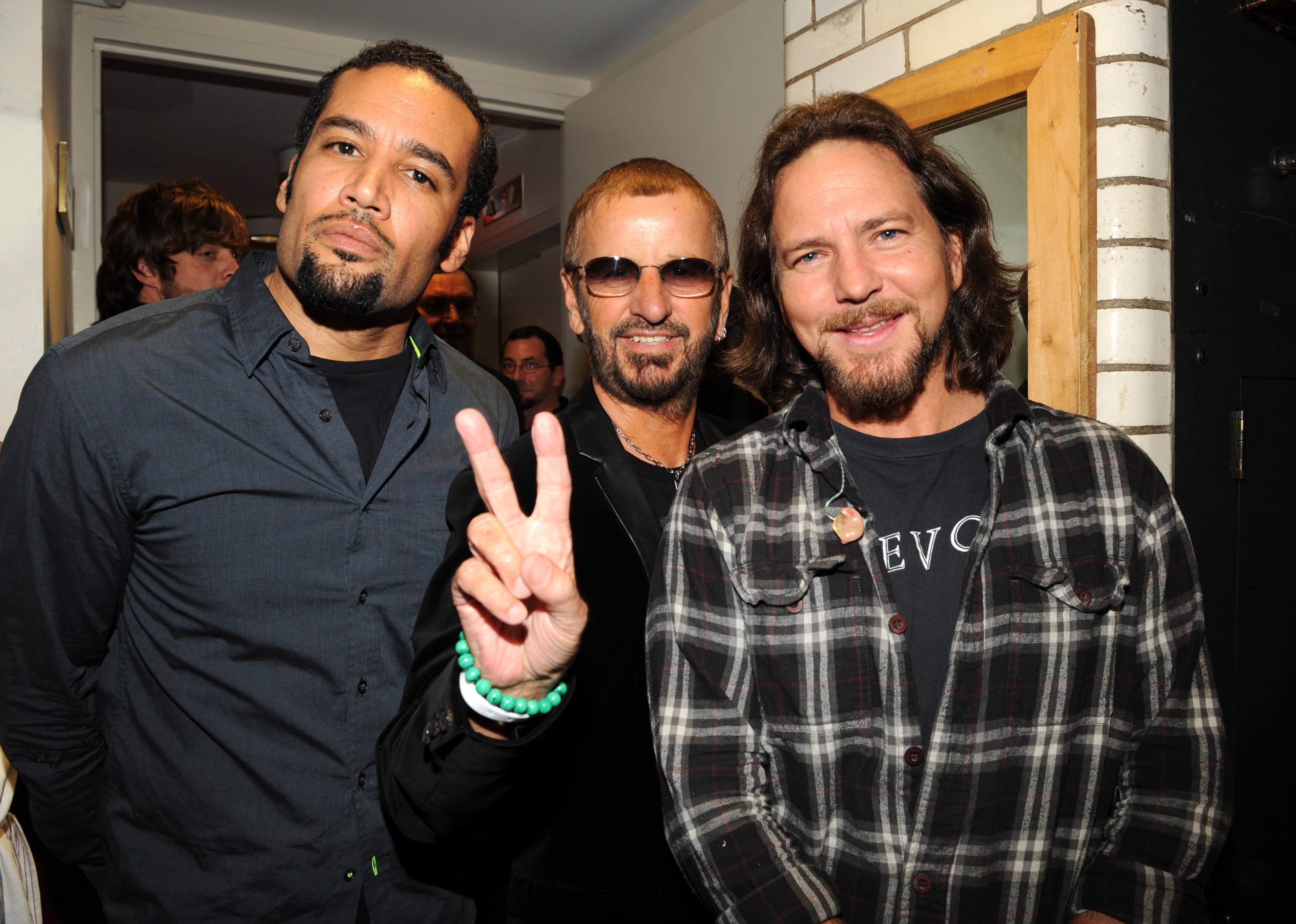 Eddie Vedder smiles, Ringo Starr makes a peace sign as they pose with Ben Harper