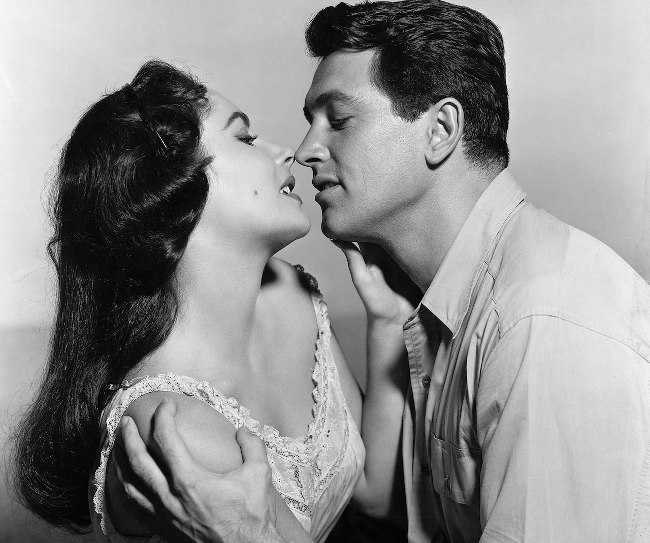 Elizabeth Taylor and Rock Hudson in a scene from the 1956 film, "Giant." They are shown in a waist-up view, embracing.