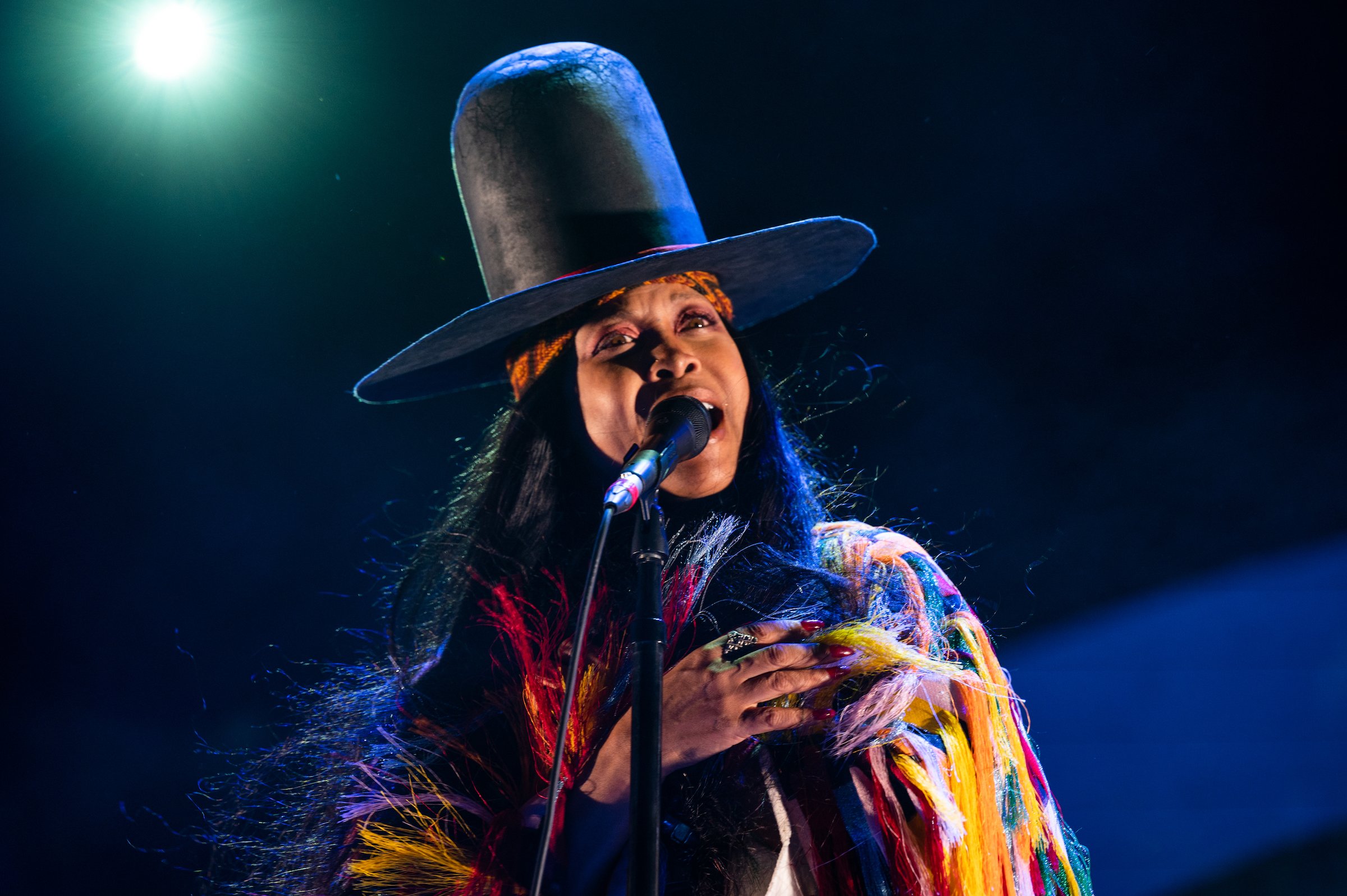 Erykah Badu wearing a tall cowboy hat and singing
