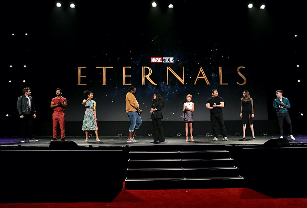 Richard Madden, Kumail Nanjiani, Lauren Ridloff, Salma Hayek, Lia McHugh, Don Lee, Angelina Jolie, and Barry Keoghan on stage in front of the ‘Eternals’ logo
